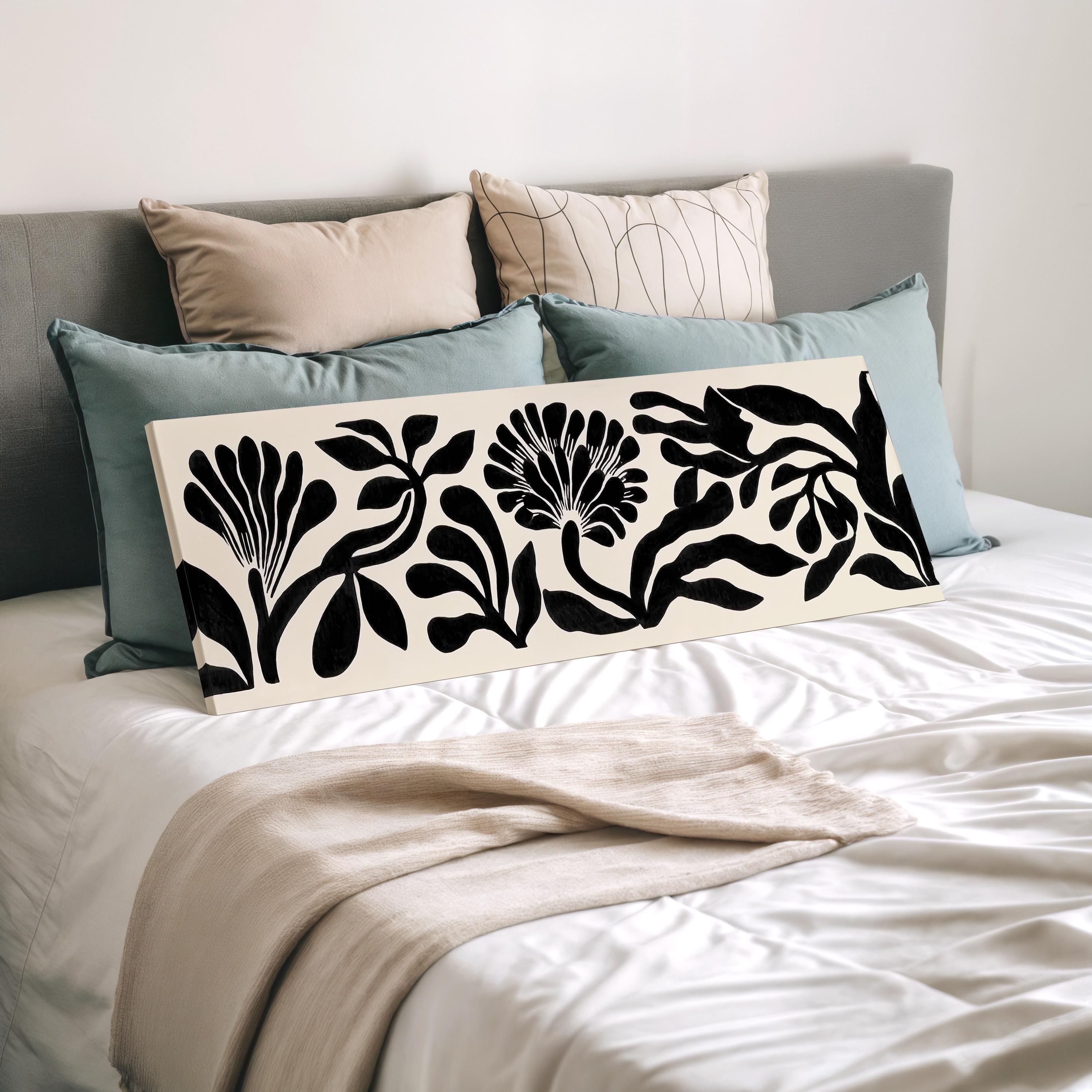 a bed with a white comforter and a black and white floral print pillow.