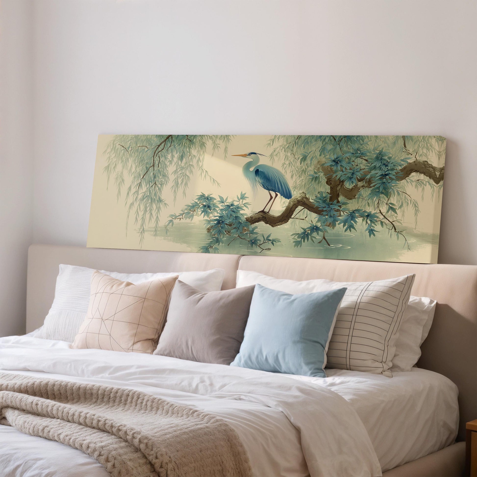 a large painting of a blue heron perched on a branch, displayed on a wall above a bed with white bedding and pillows.