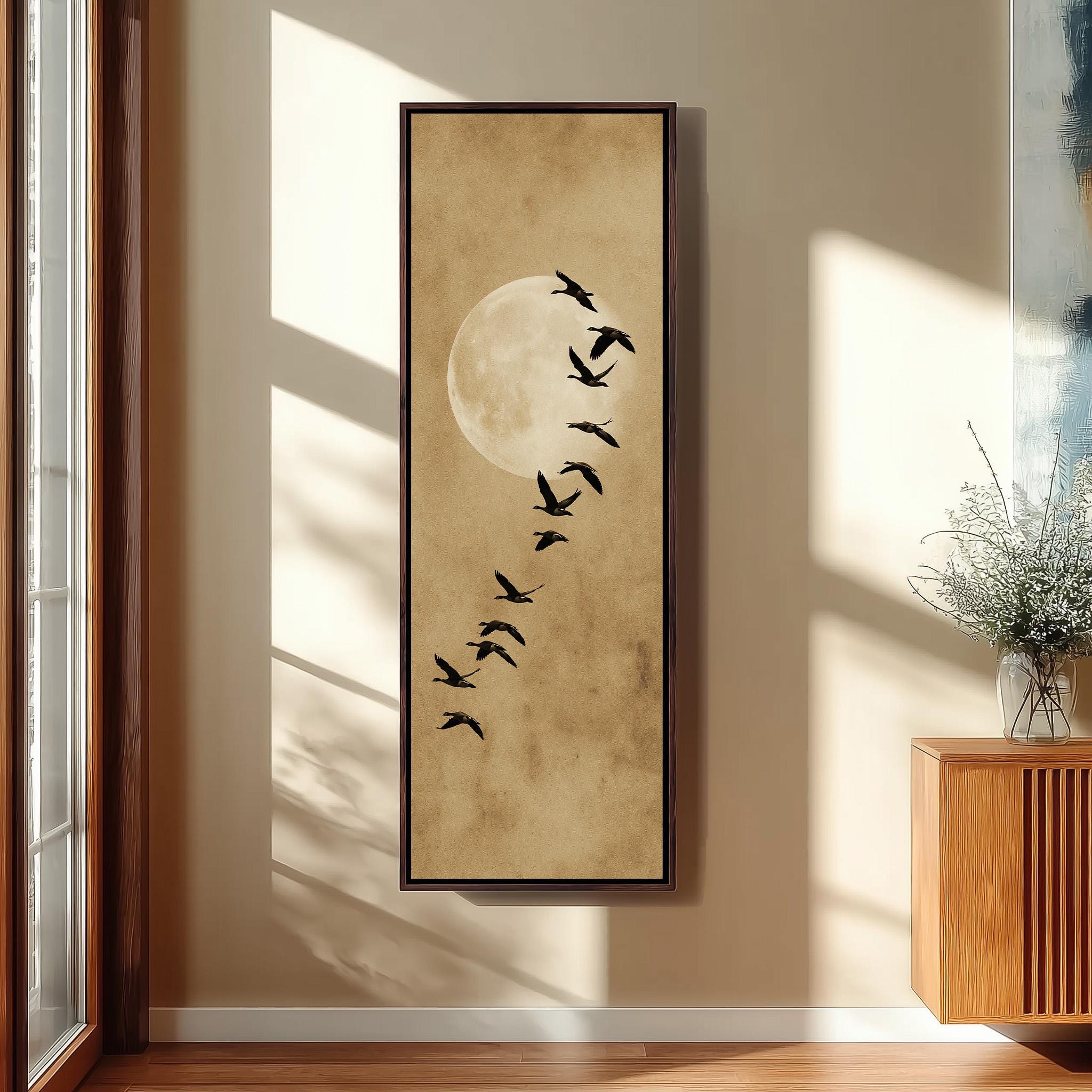 a large framed artwork depicting a flock of birds flying in a line, with a large moon in the background.
