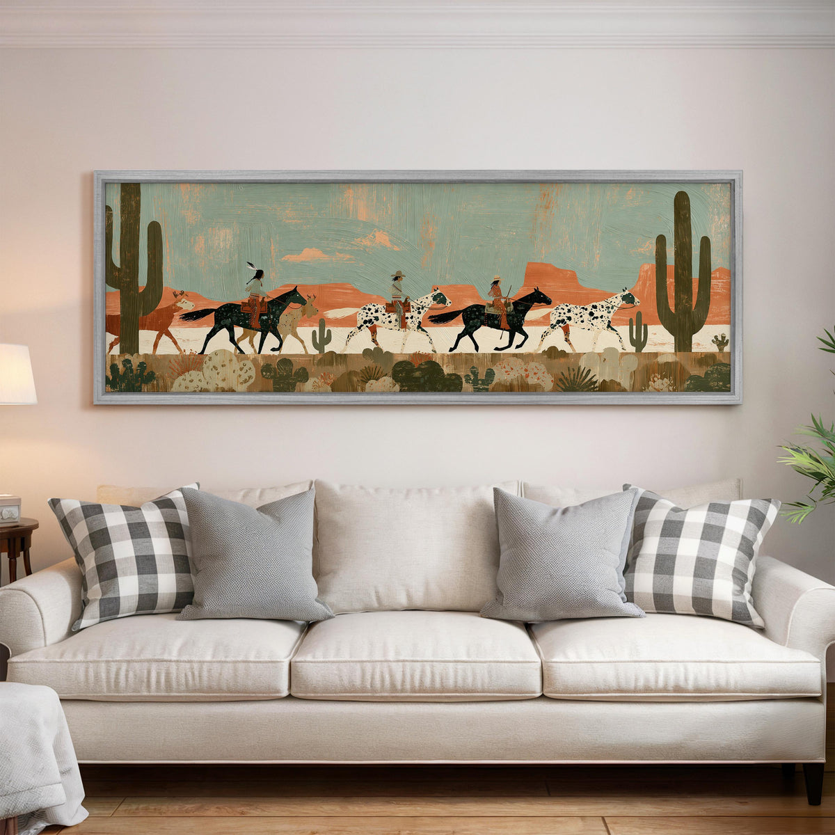 Riders on spotted horses across a red rock desert panoramic canvas print above a white sofa in a bright living room