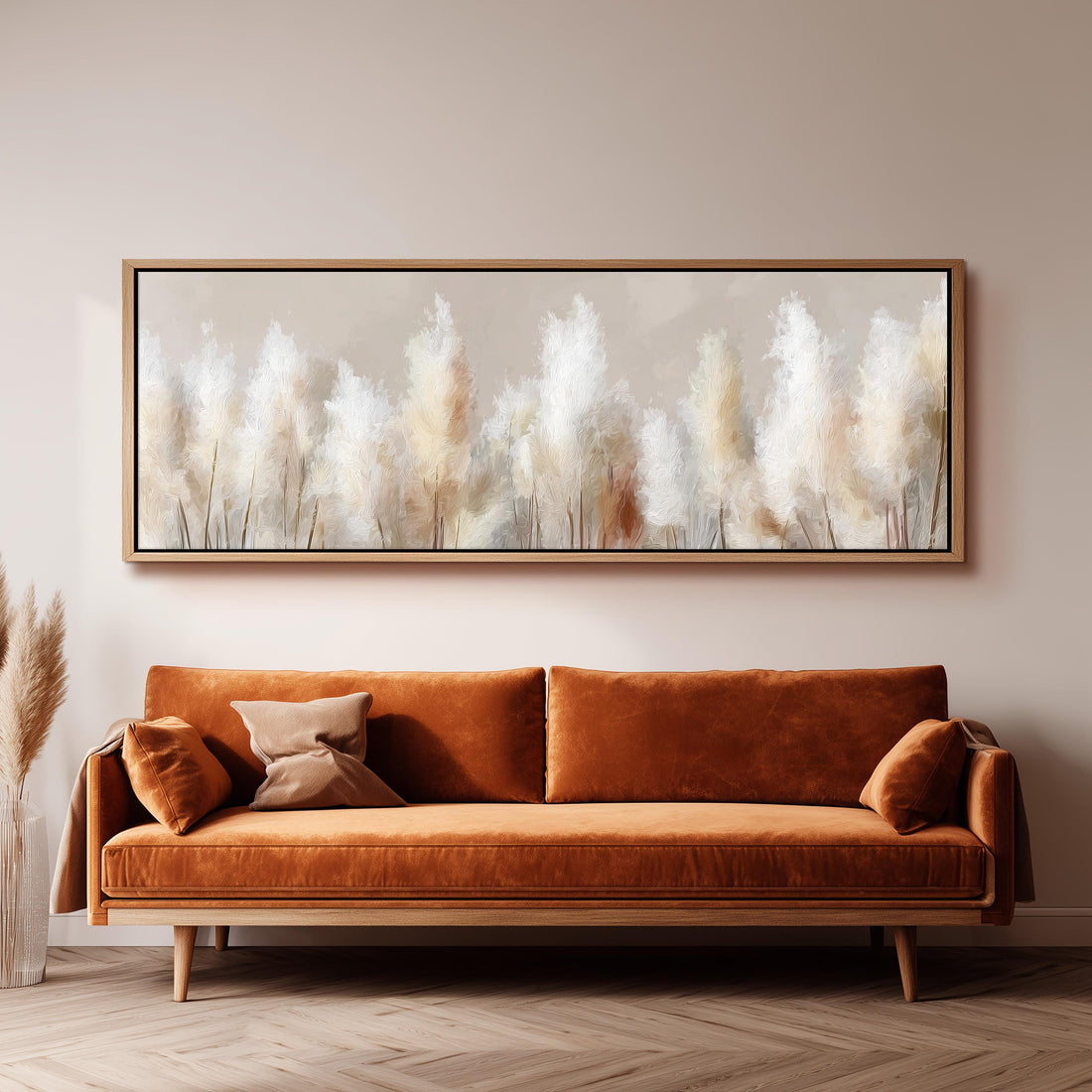 a large, framed painting of tall, white flowers hanging on a wall above a brown sofa with orange cushions.