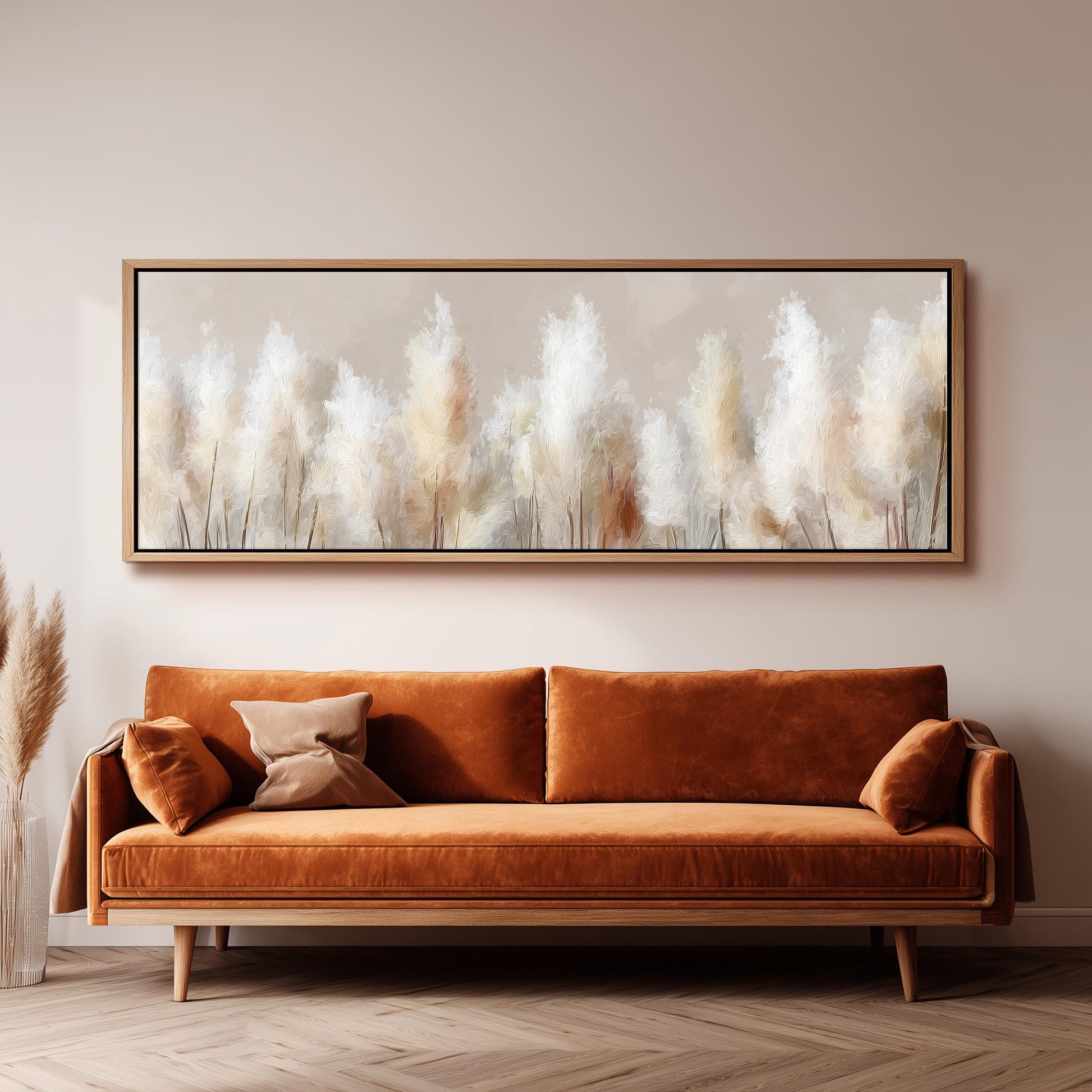a large, framed painting of tall, white flowers hanging on a wall above a brown sofa with orange cushions.