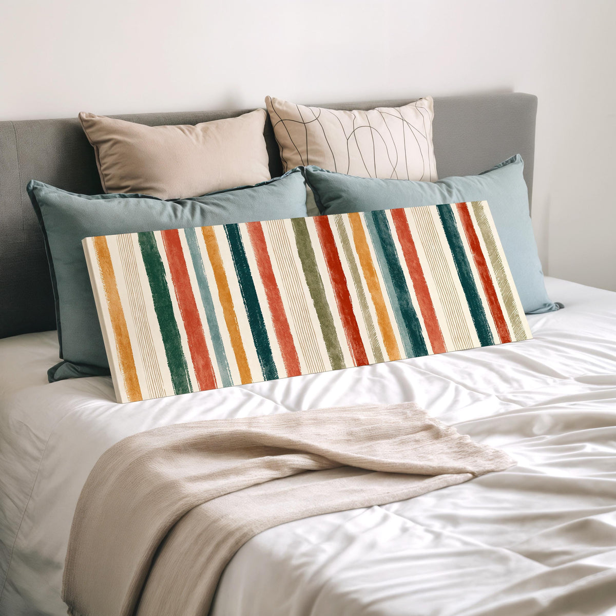 Boho watercolor stripes in mustard, teal and rust wide panoramic canvas print laid on a bed to show its size