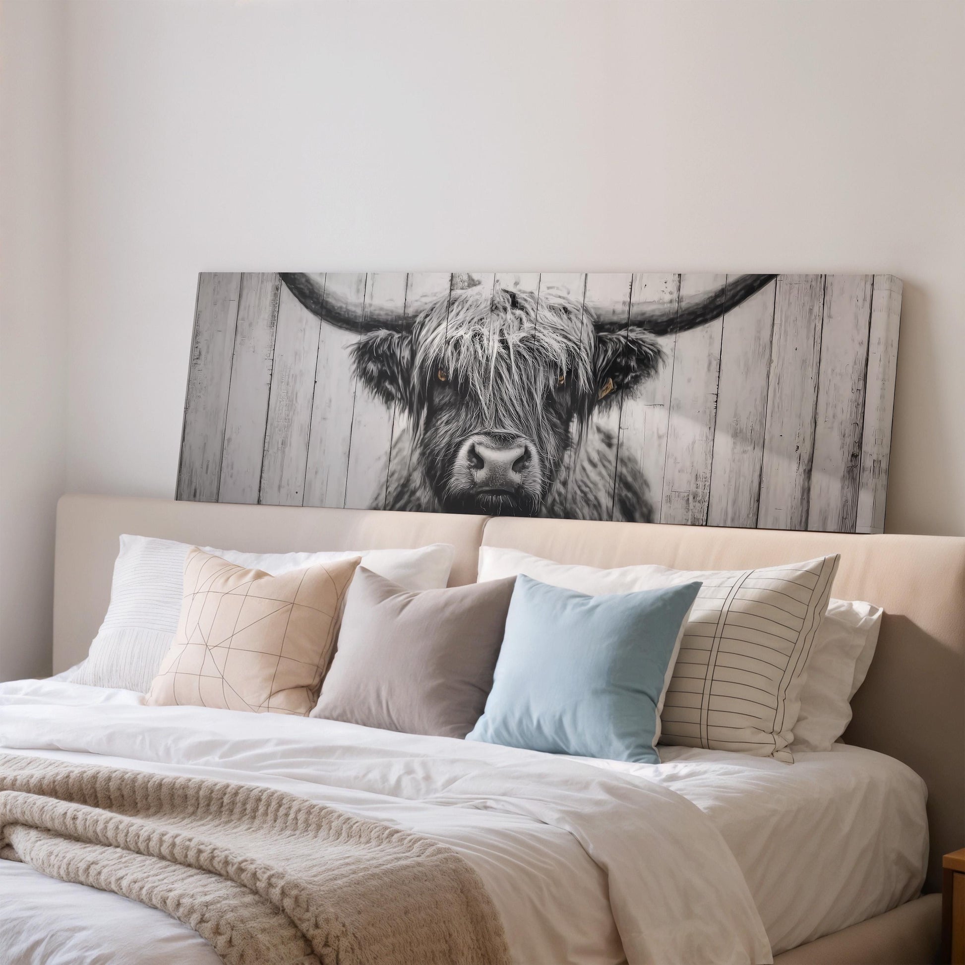 a large black and white photograph of a cow's head on a wall above a bed with white bedding and pillows.