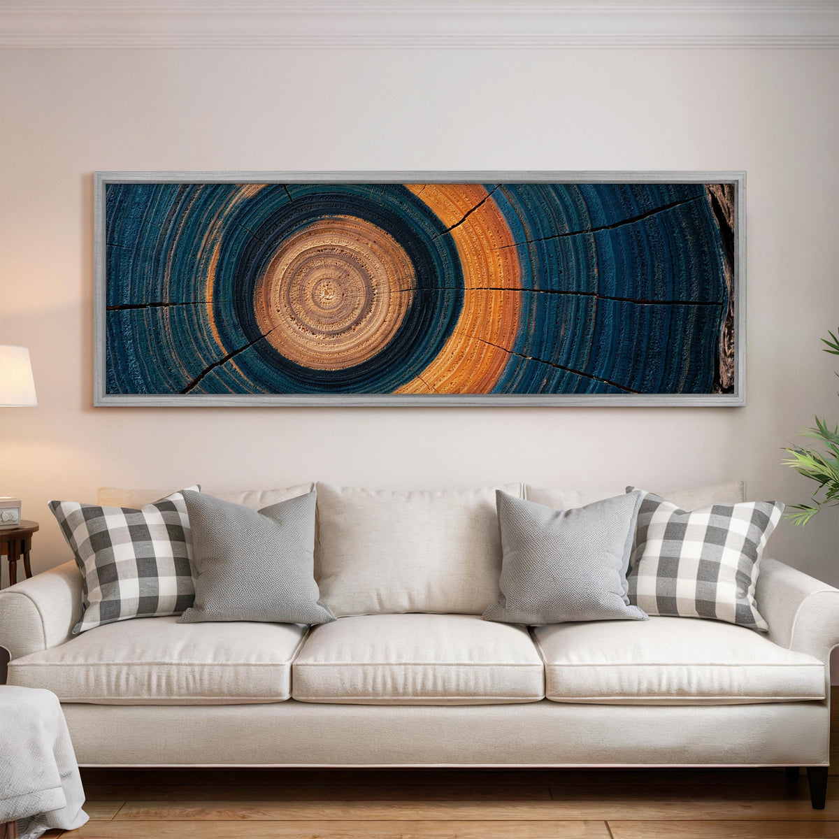 Teal and orange tree ring panoramic canvas print above a white sofa in a bright living room