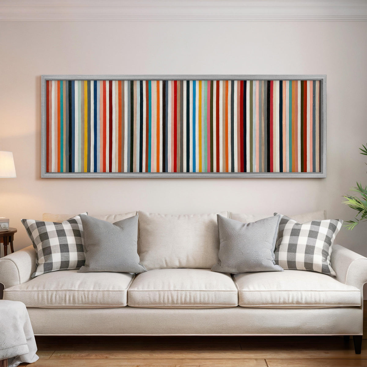 Rainbow pinstripes panoramic canvas print above a white sofa in a bright living room