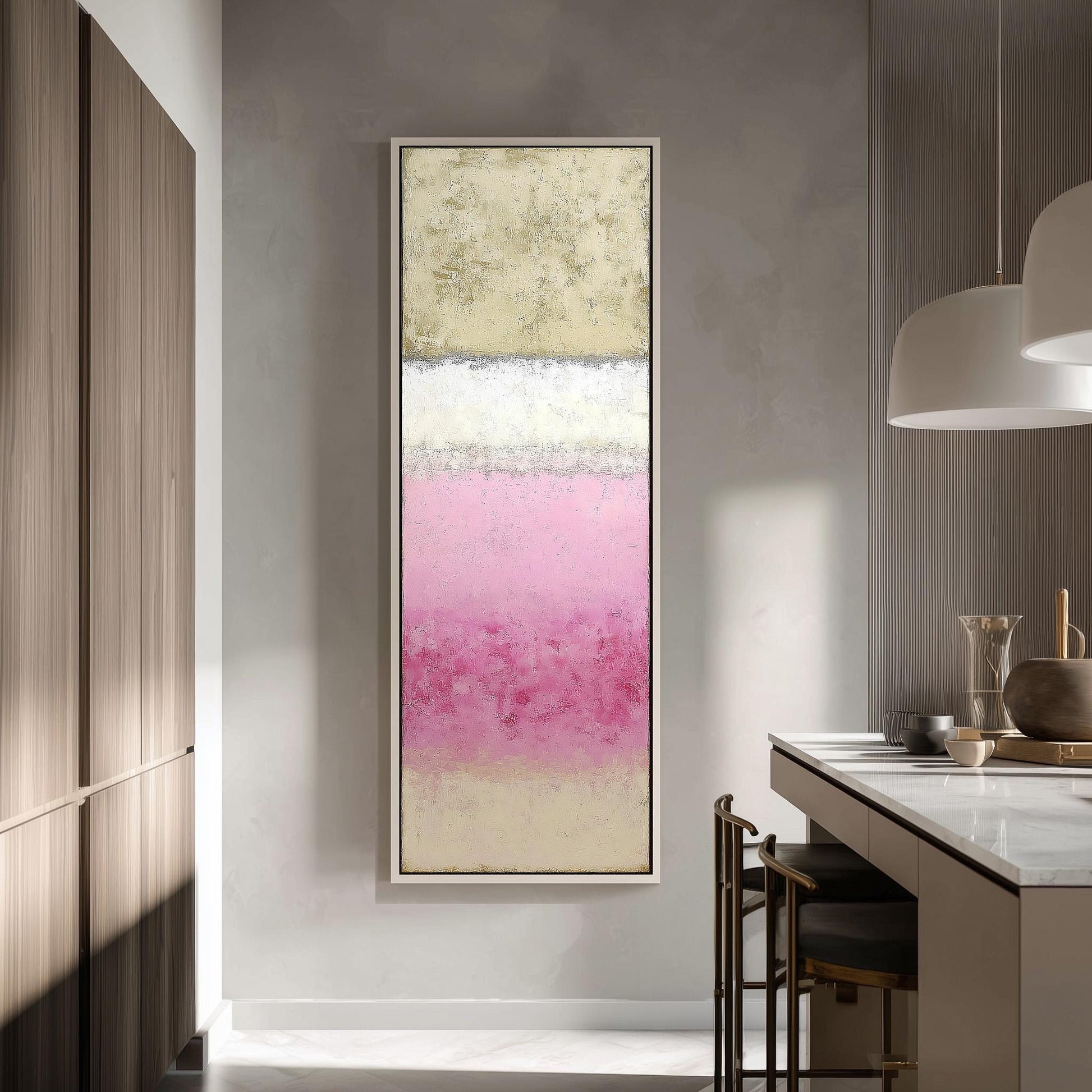 a modern kitchen with a large abstract painting hanging on the wall. The painting has a pink and white color scheme and is framed in a white frame. The kitchen has a white countertop and a wooden cabinet, creating a clean and minimalist aesthetic.