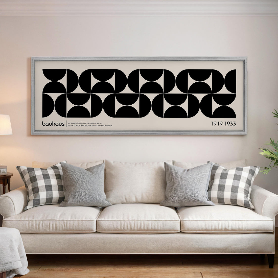 a large black and white abstract artwork hanging on a wall above a white sofa with gray and white throw pillows.