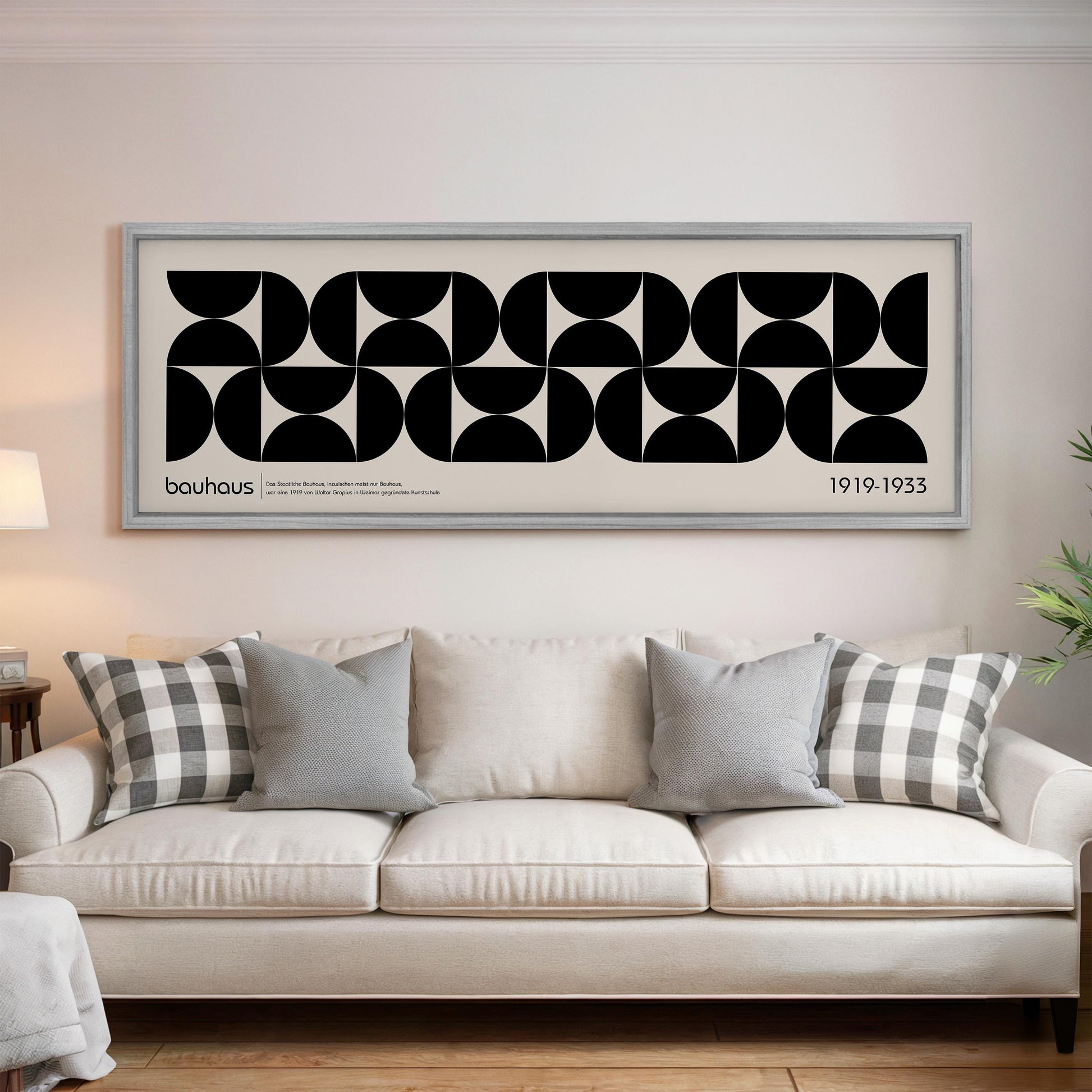 a large black and white abstract artwork hanging on a wall above a white sofa with gray and white throw pillows.