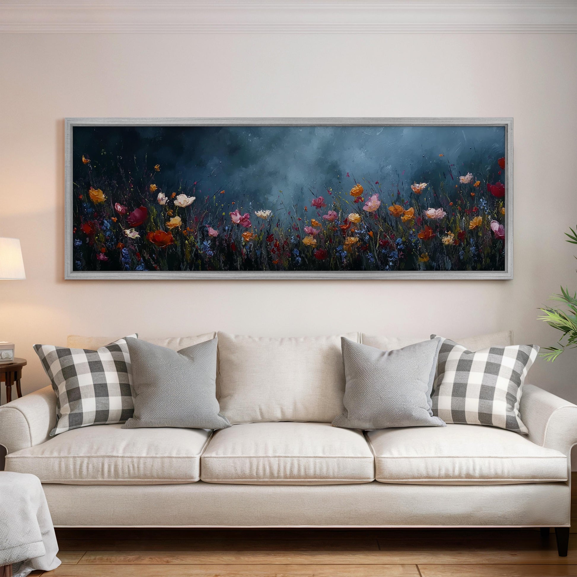a large, framed painting of a field of flowers hanging on a wall above a white couch with gray and white plaid throw pillows.