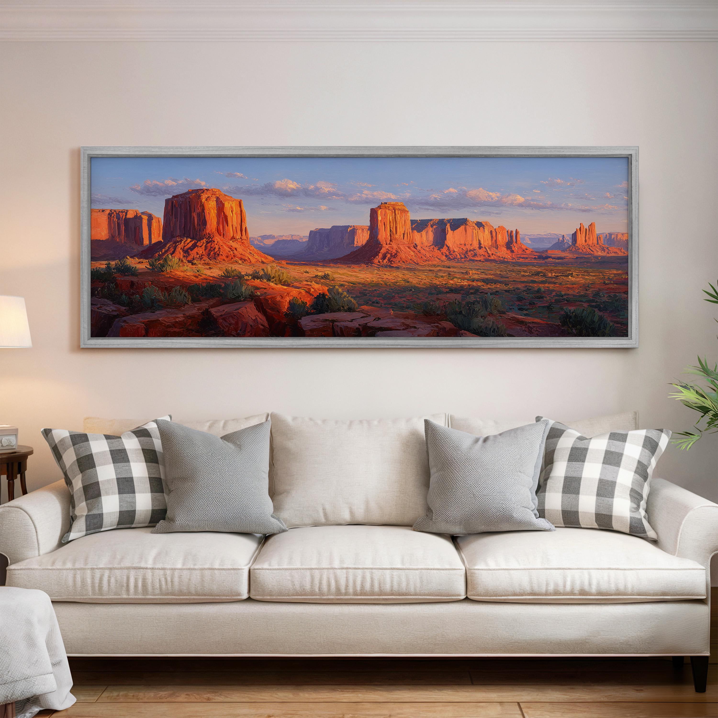a large framed landscape painting hanging on a wall above a white couch with gray and white patterned pillows.