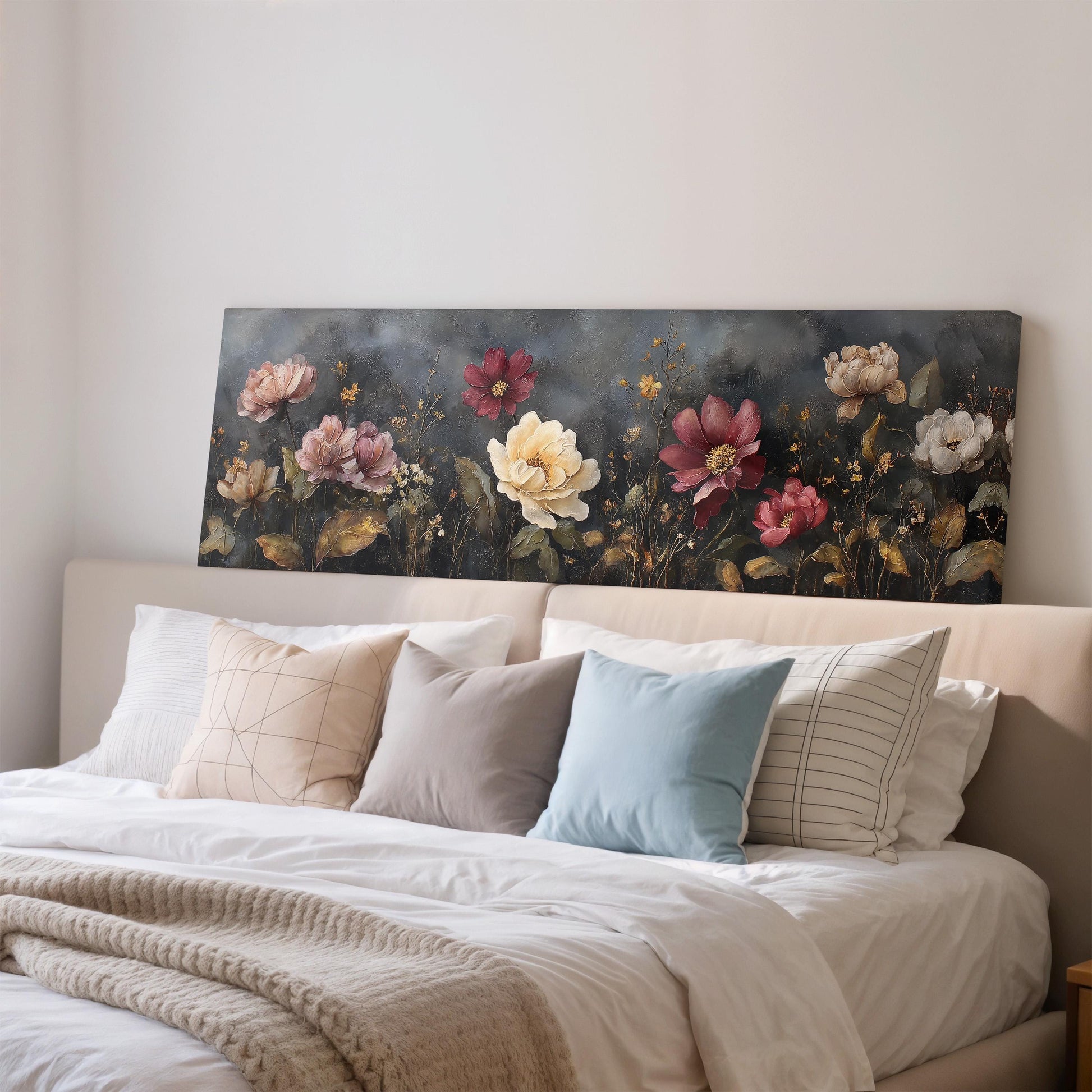 a large floral painting hanging on a wall above a bed with white bedding and various pillows.
