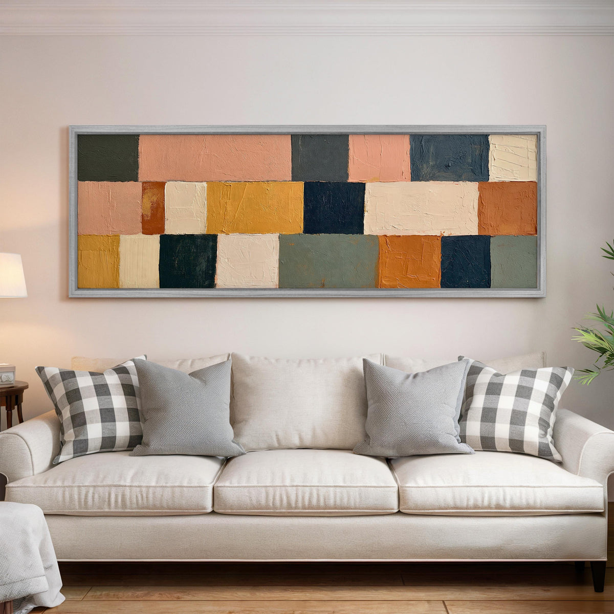 Mustard, sage, blush and navy patchwork panoramic canvas print above a white sofa in a bright living room