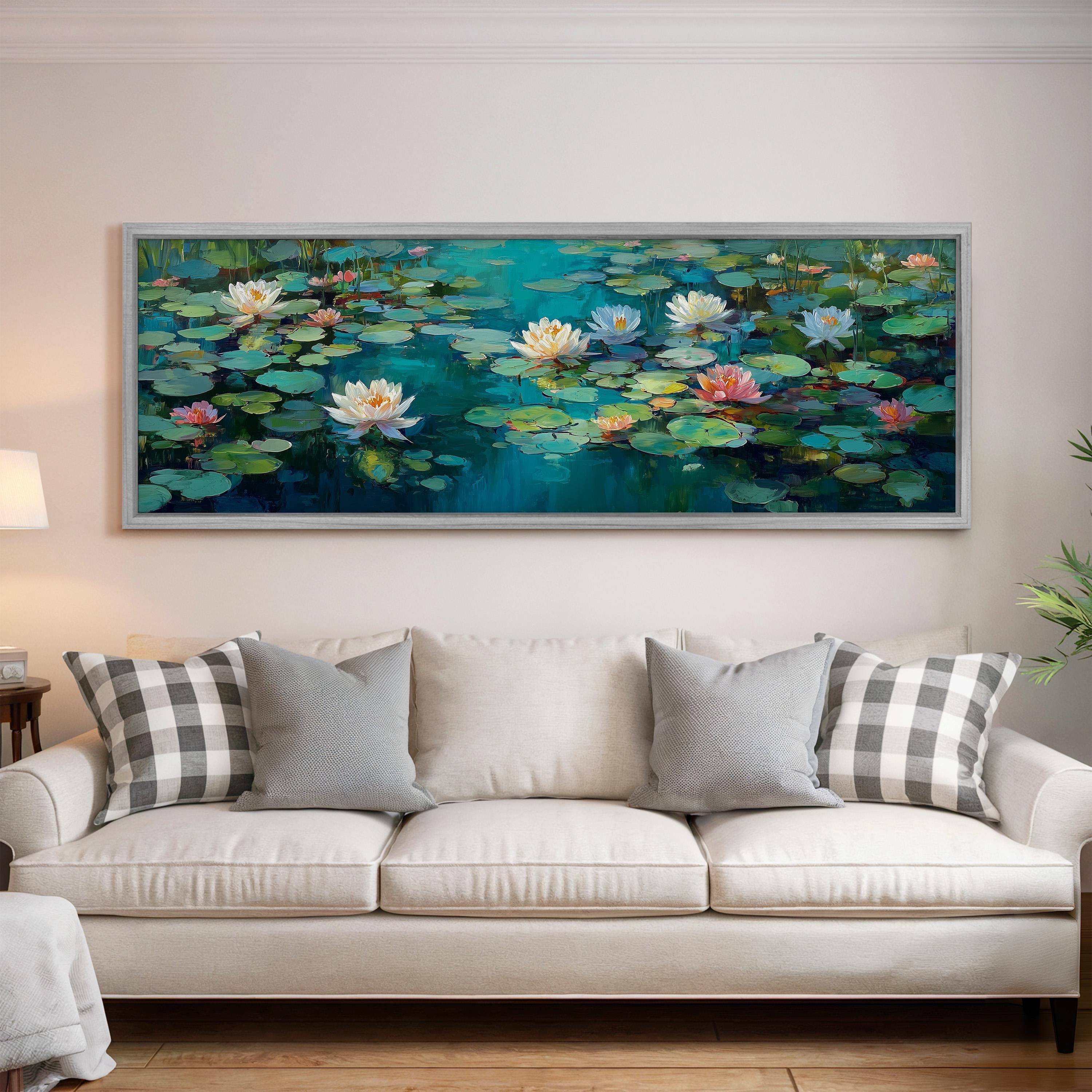 a large painting of lily pads hanging on a wall above a white couch with gray and white pillows.