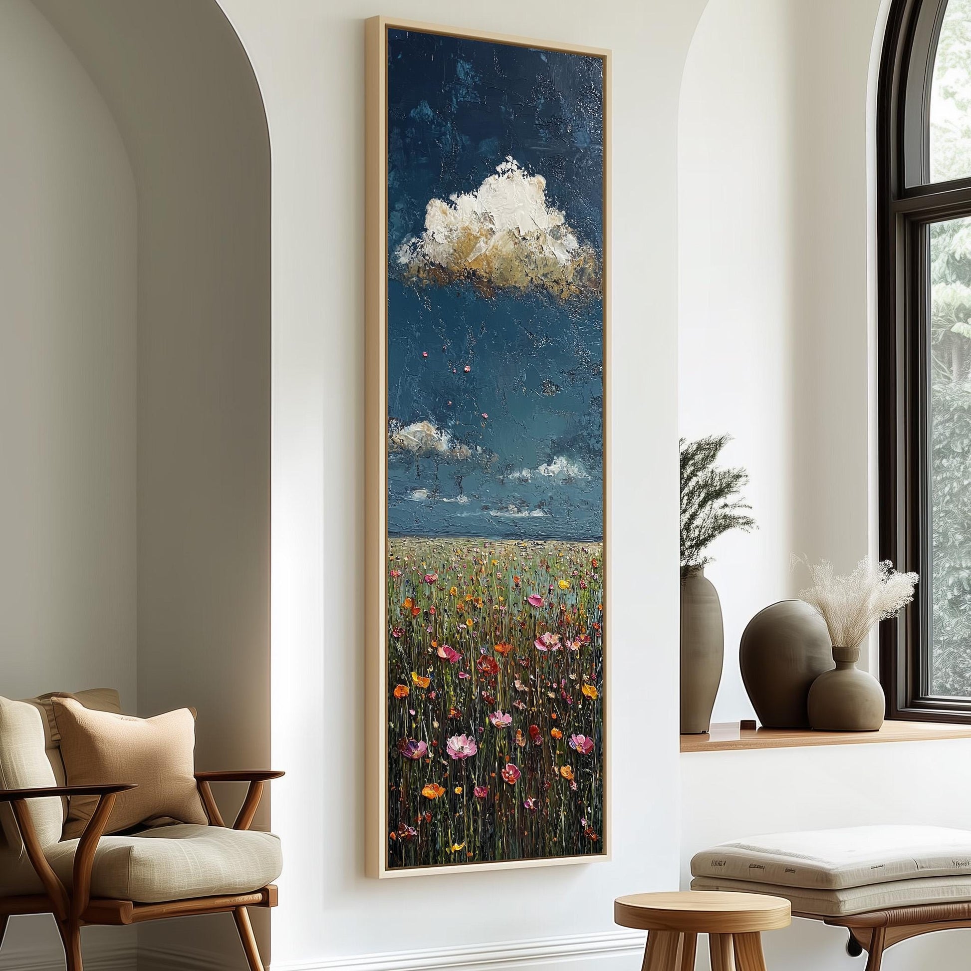 a large painting of a field with flowers hanging on a wall, accompanied by a wooden chair and a small table in a room with a window.