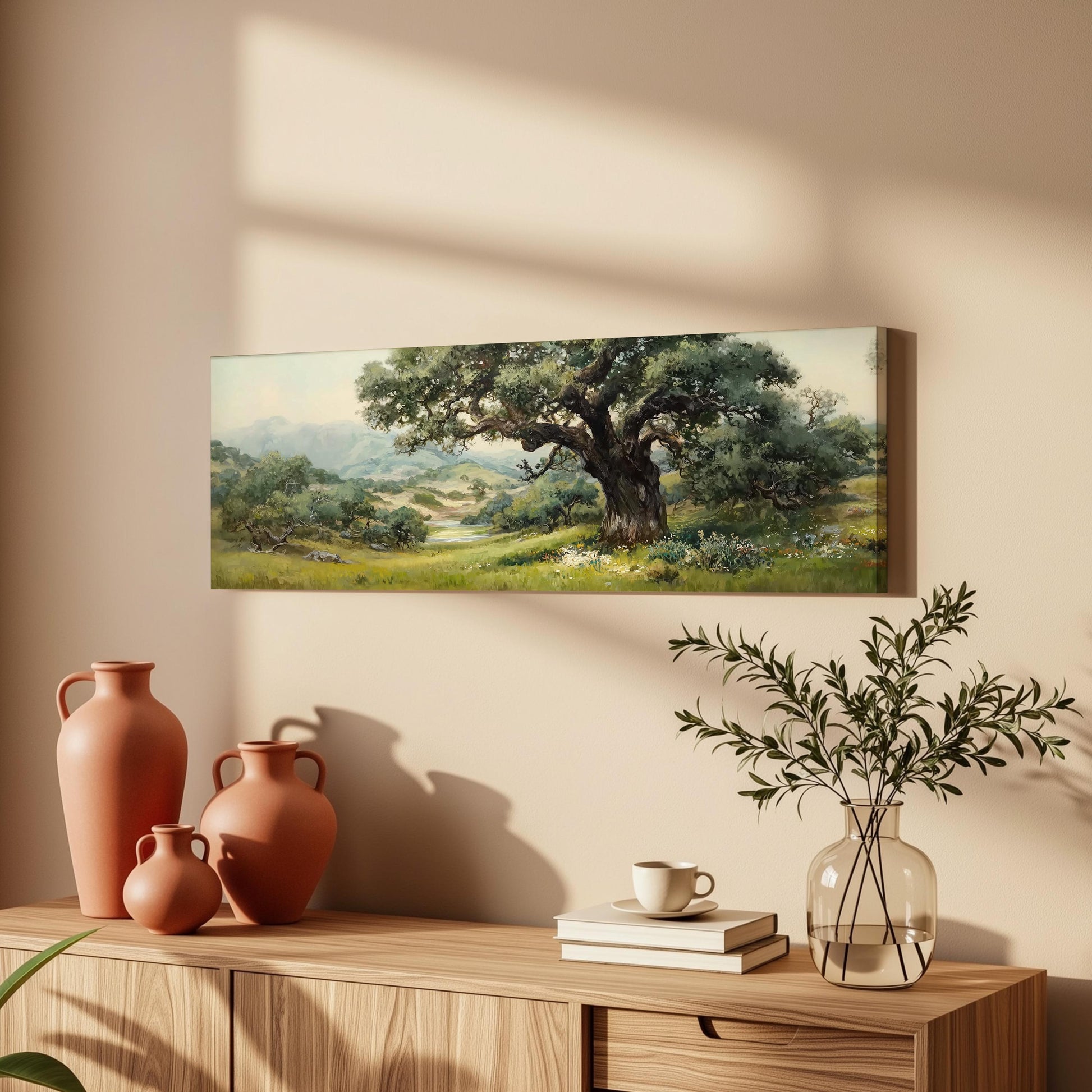 a wooden cabinet with a painting of a large tree hanging on the wall above it. The cabinet also has three orange vases and a glass vase with greenery on top.