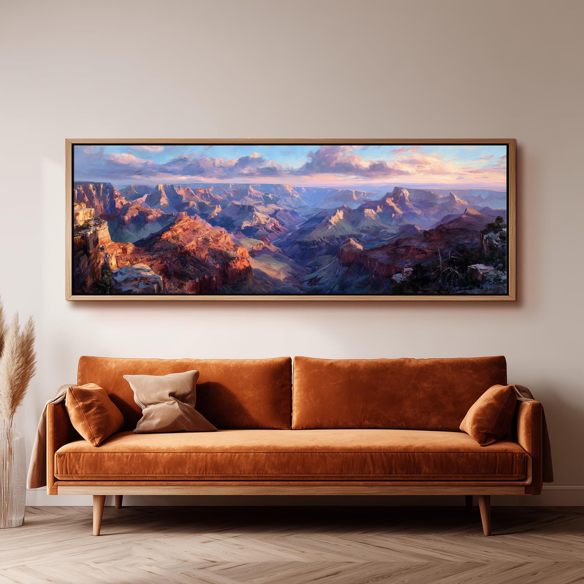 a large, framed painting of a mountainous landscape hanging on a wall above a brown sofa.