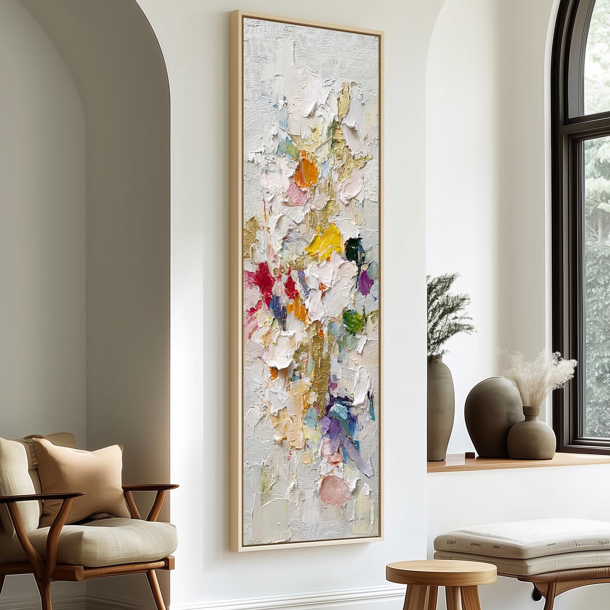 a large, colorful painting hanging on a white wall in a room with a wooden chair and a small table.