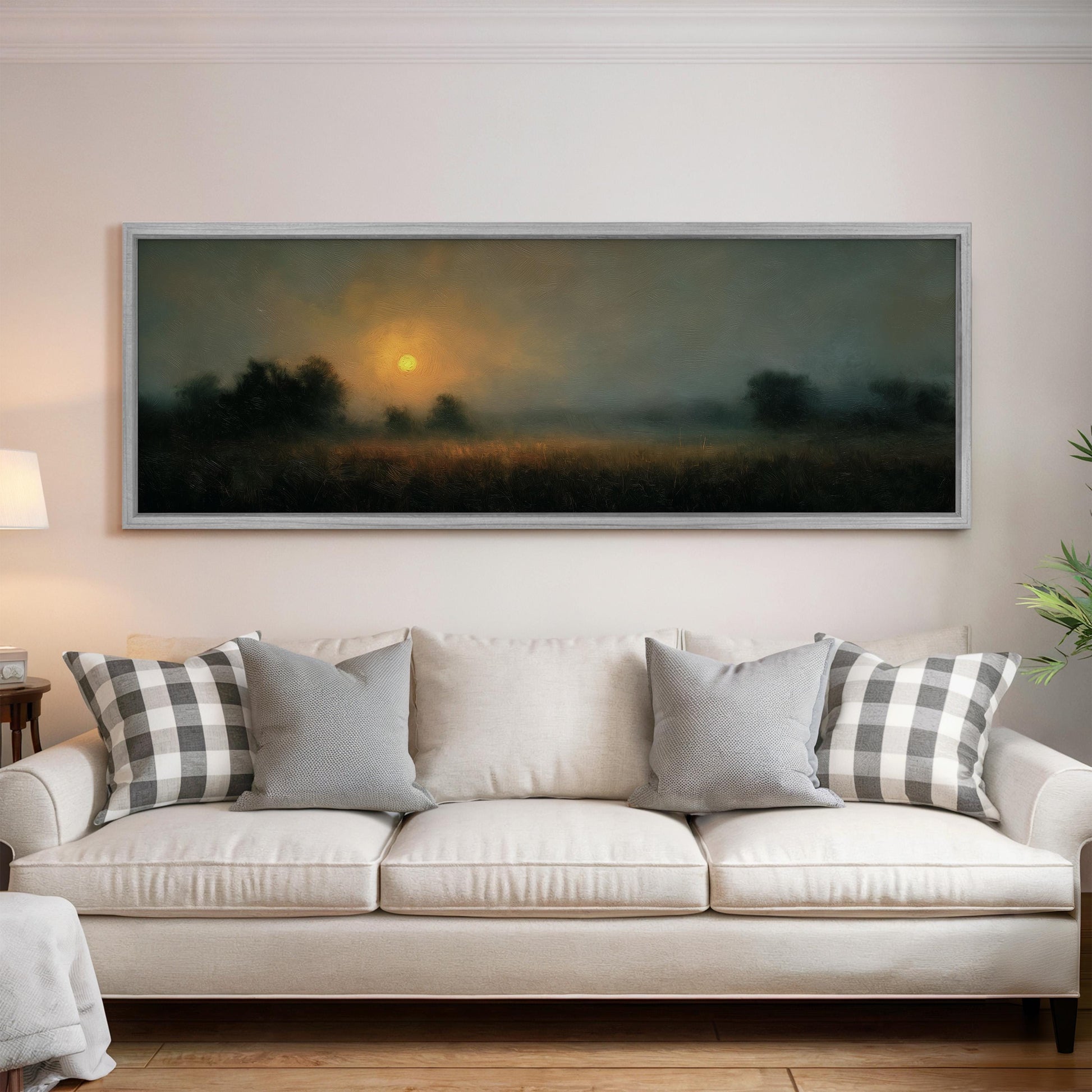 a large, framed landscape painting hanging on a wall above a white sofa with gray and white patterned throw pillows.