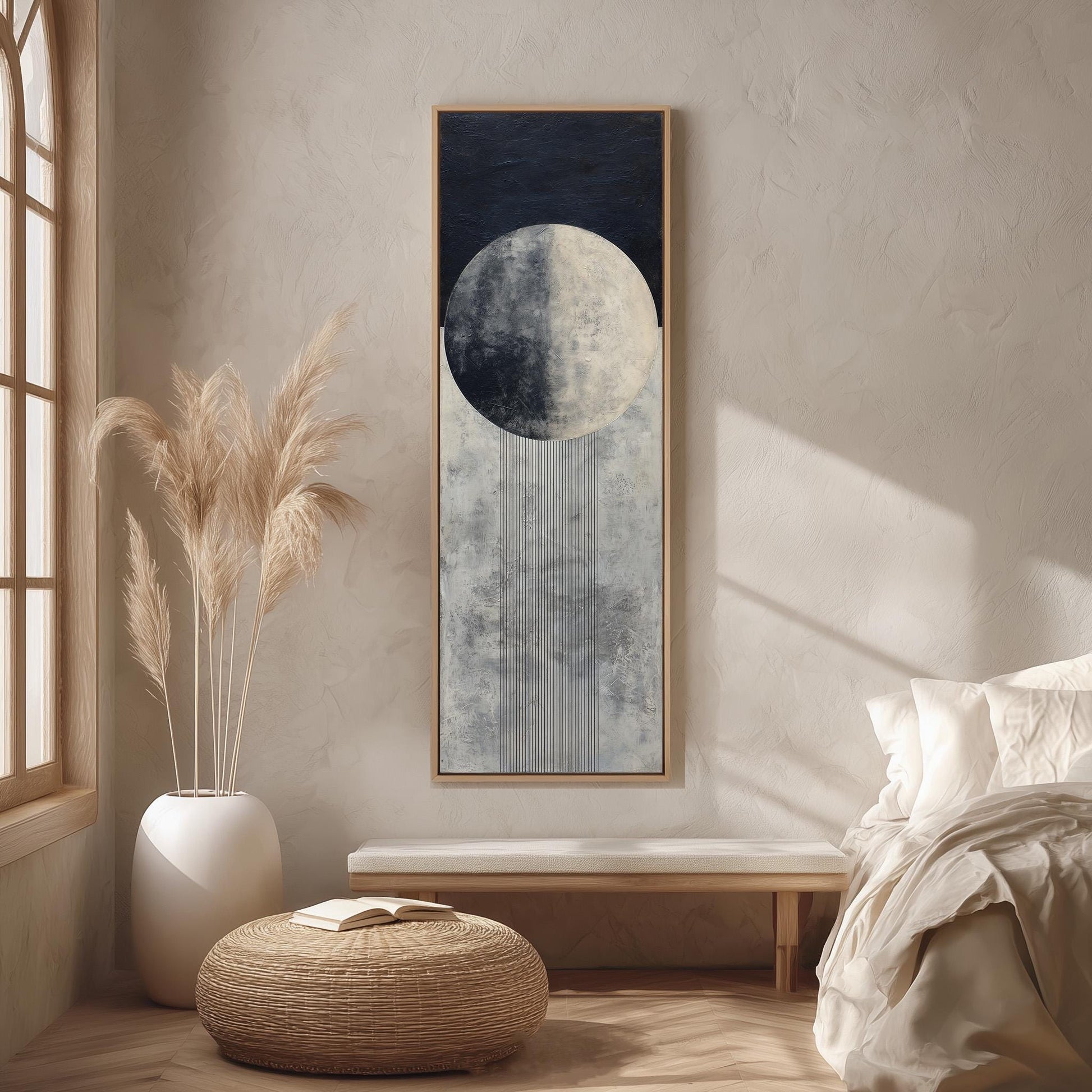 a serene and minimalist bedroom with a large window, a bed with white bedding, a wicker ottoman, and a framed artwork of a moon and a crescent moon hanging on the wall.