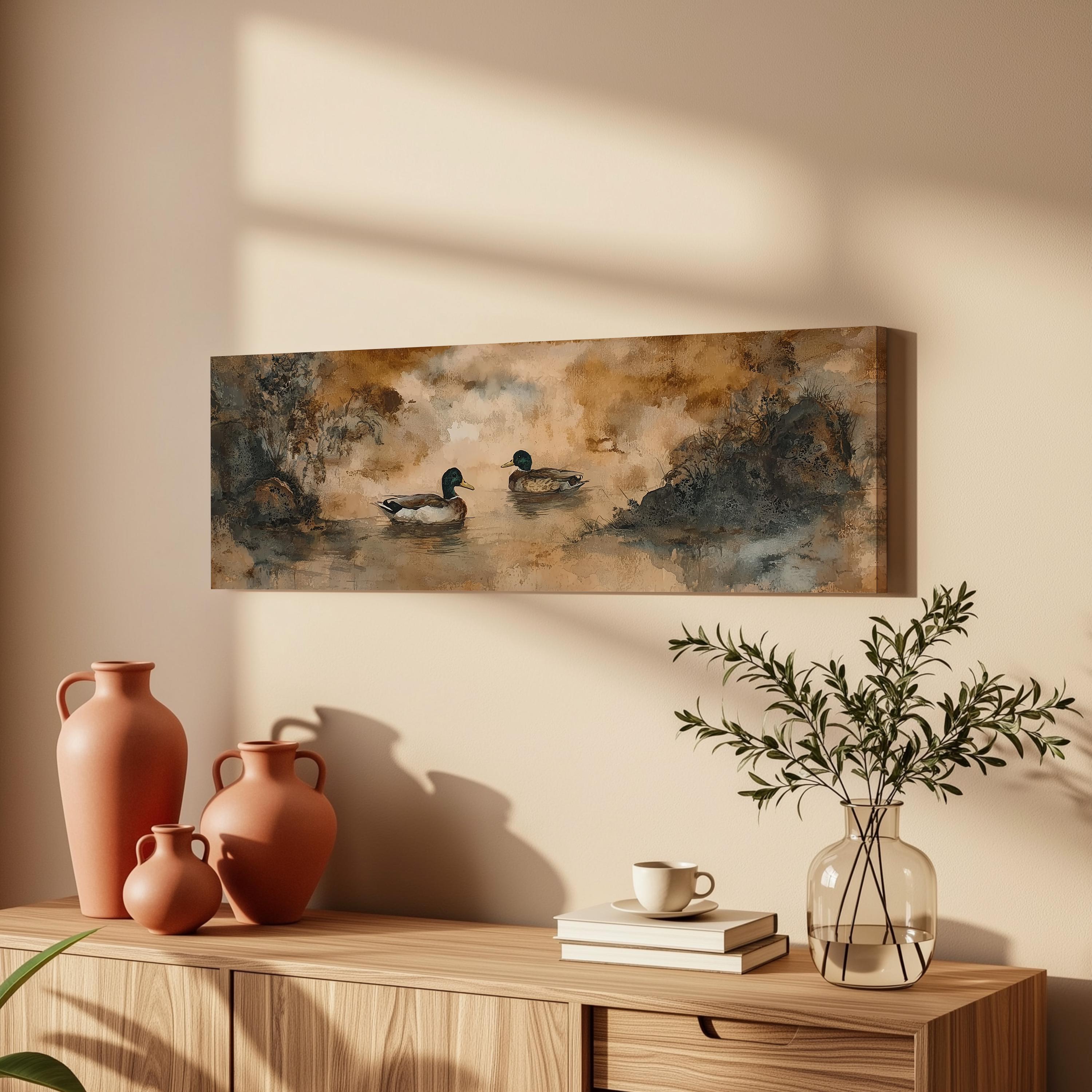 a wooden cabinet with a painting of ducks swimming in a pond hanging on the wall above it. The cabinet also has three orange vases, a white coffee cup, and a stack of books on top.