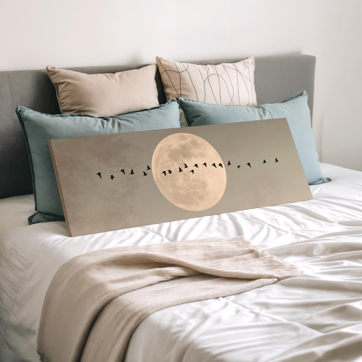 Geese crossing a full moon on grey wide panoramic canvas print laid on a bed to show its size