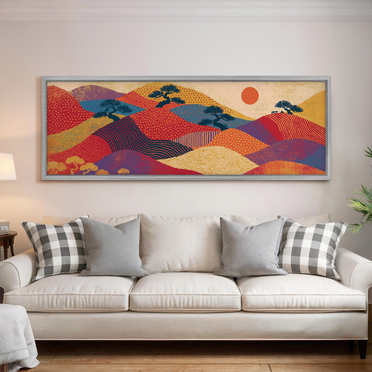 Bonsai trees on patterned hills with a red sun panoramic canvas print above a white sofa in a bright living room