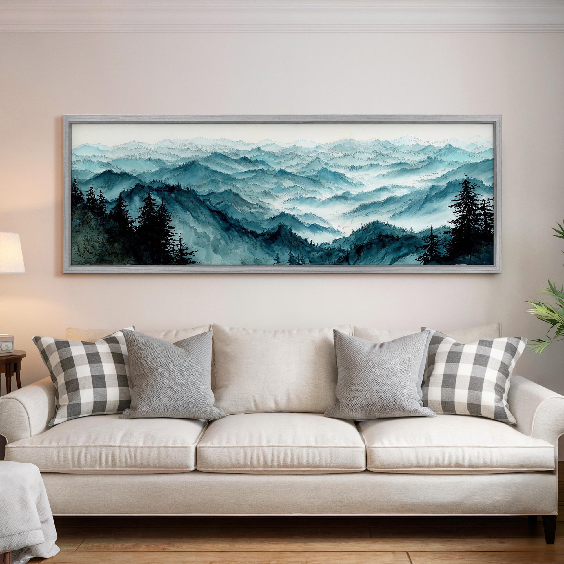 a large framed landscape painting hanging on a wall above a white sofa with gray and white patterned pillows.