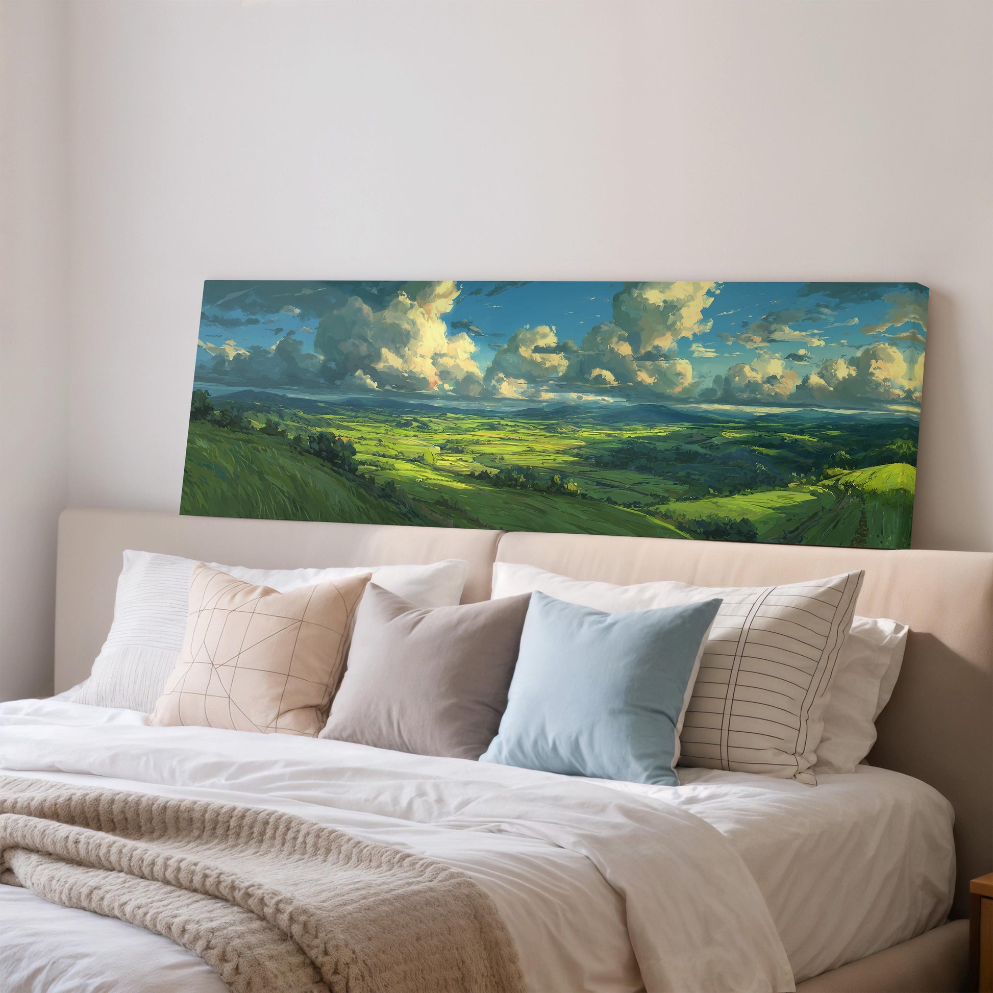 a large landscape painting hanging on a wall above a bed with white pillows and a gray blanket.