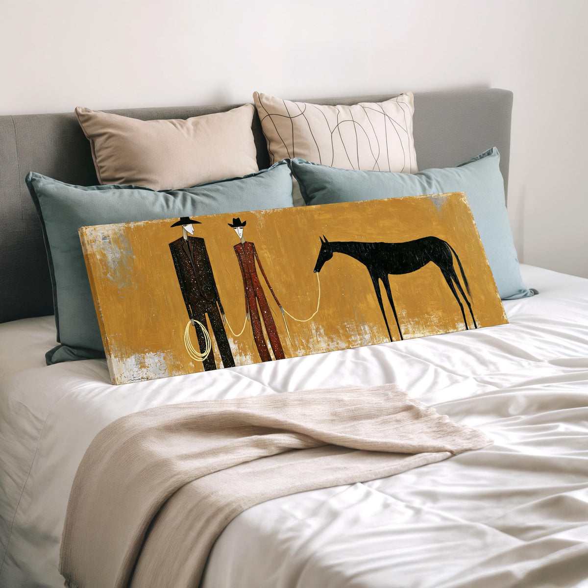 Two cowboys with a dark horse on gold wide panoramic canvas print laid on a bed to show its size