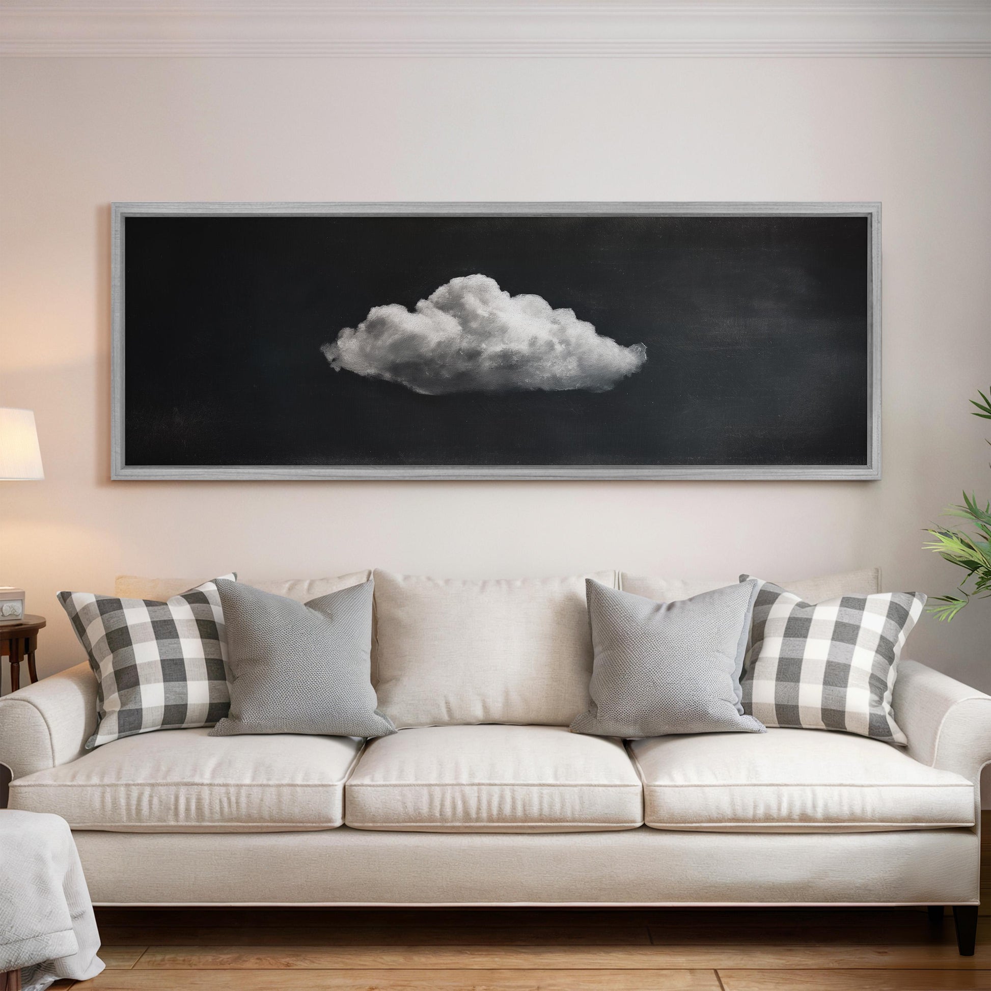 a large black and white photograph of a cloud hanging on the wall above a white sofa with gray and white patterned pillows.