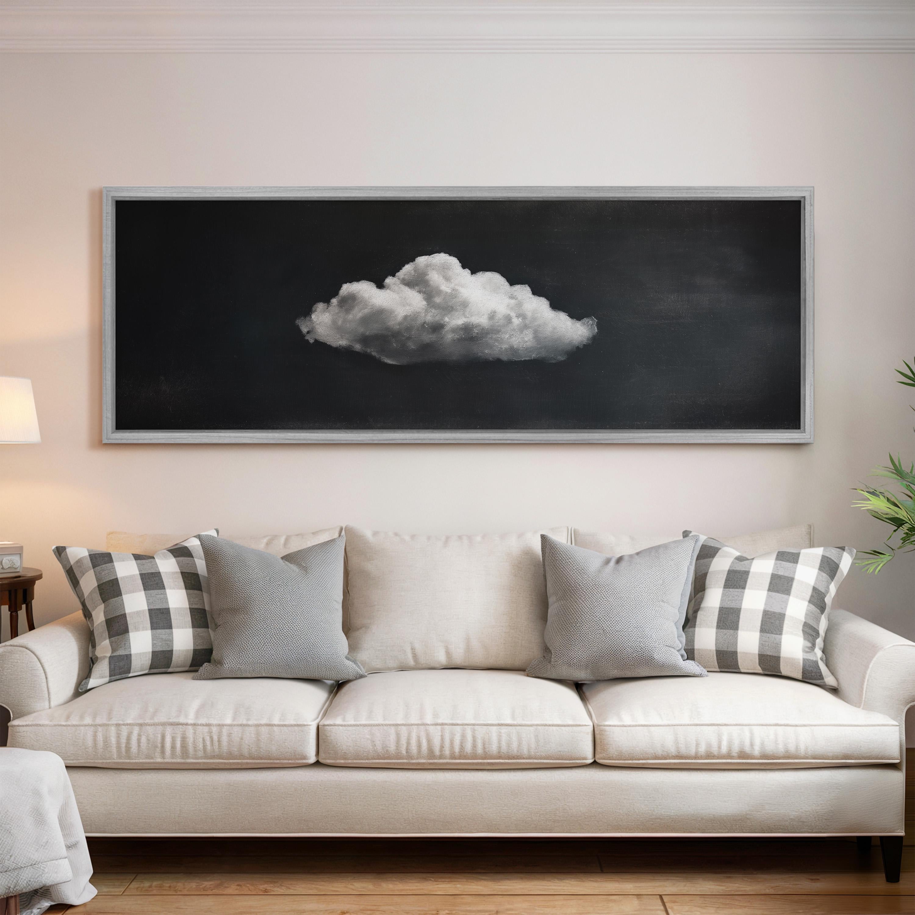 a large black and white photograph of a cloud hanging on the wall above a white sofa with gray and white patterned pillows.