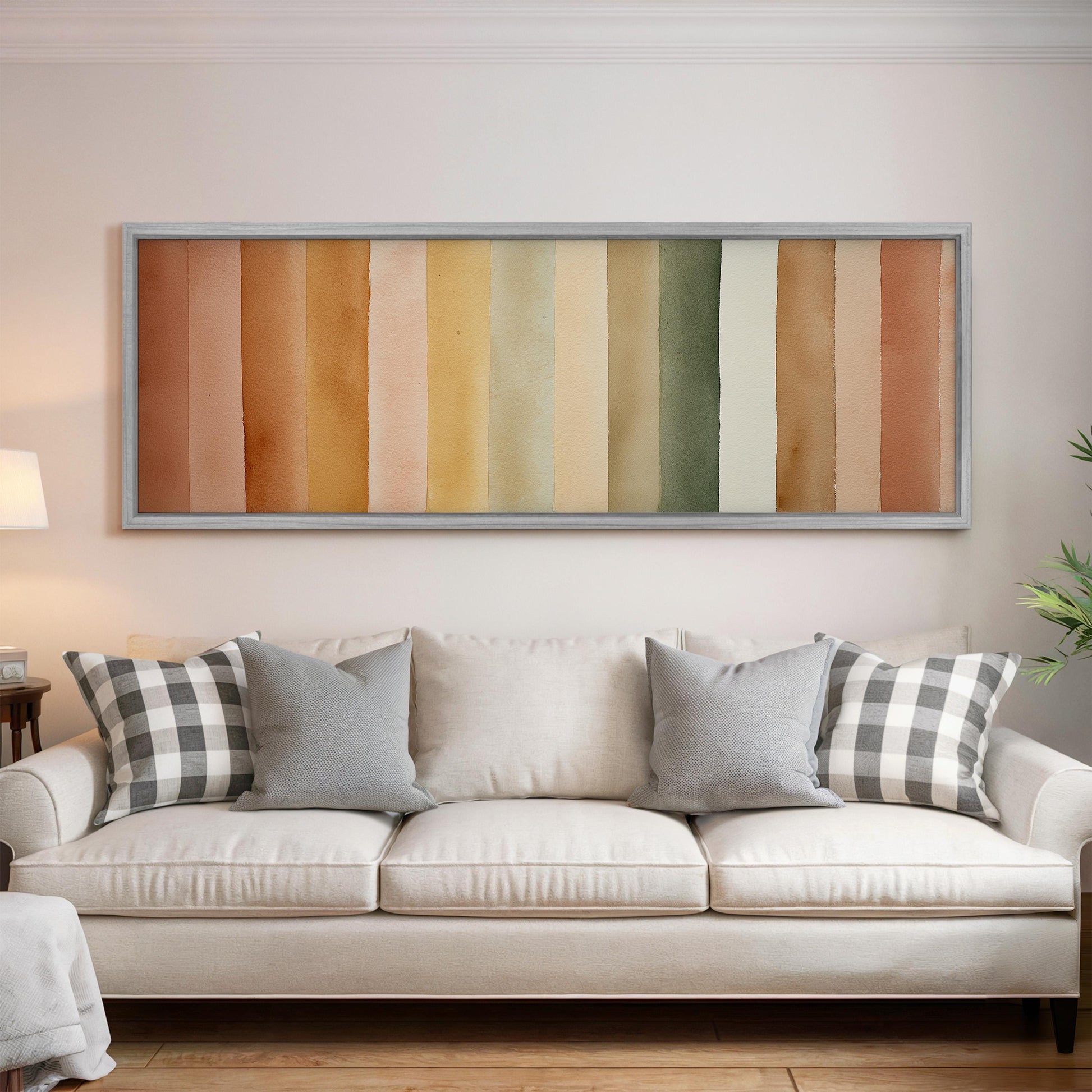 a cozy living room with a white sofa adorned with gray and black plaid throw pillows. Above the sofa, there is a large framed artwork depicting a gradient of colors, creating a visually appealing focal point in the room.