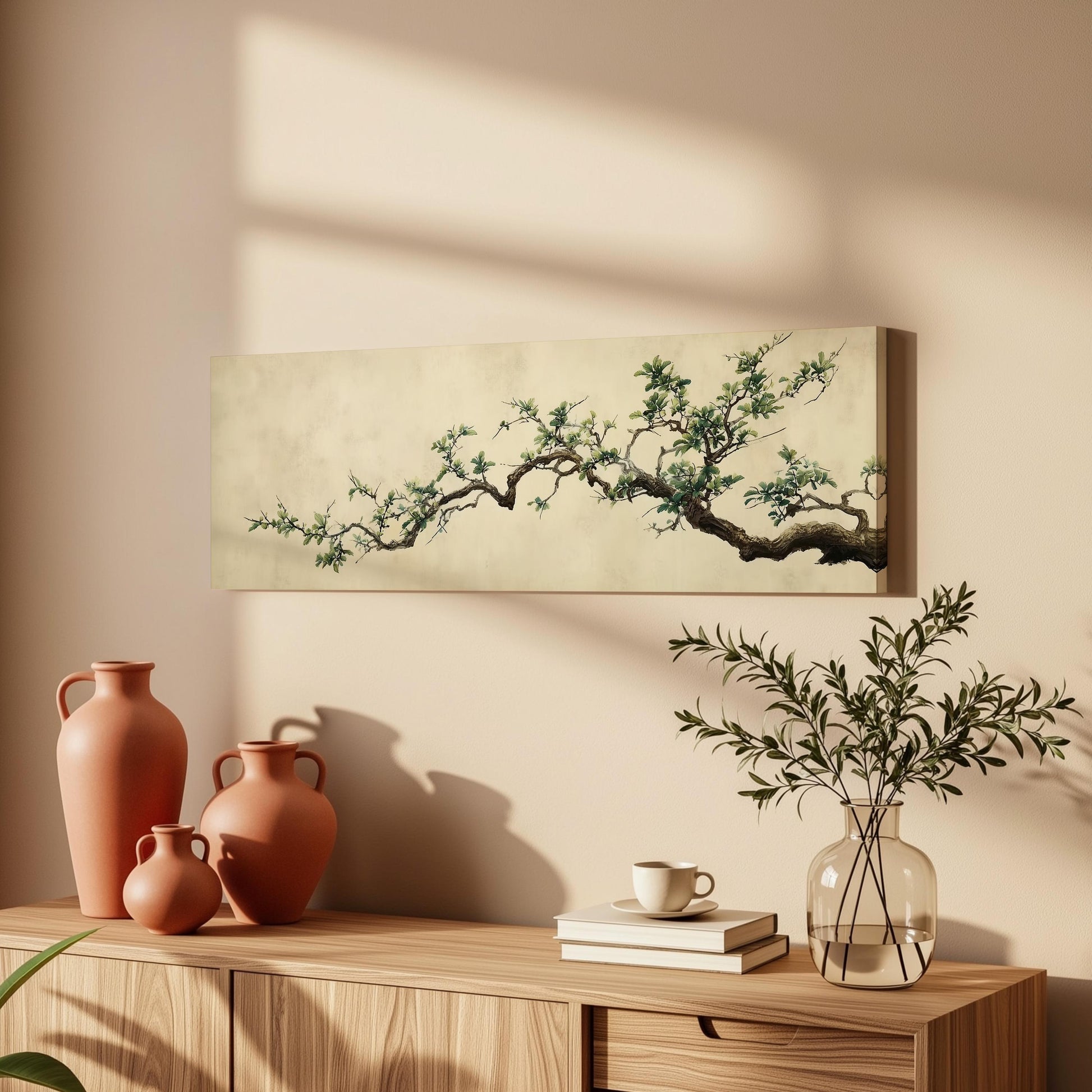 a wooden cabinet with a painting of a tree branch hanging on the wall above it, along with three orange vases and a glass vase with greenery.