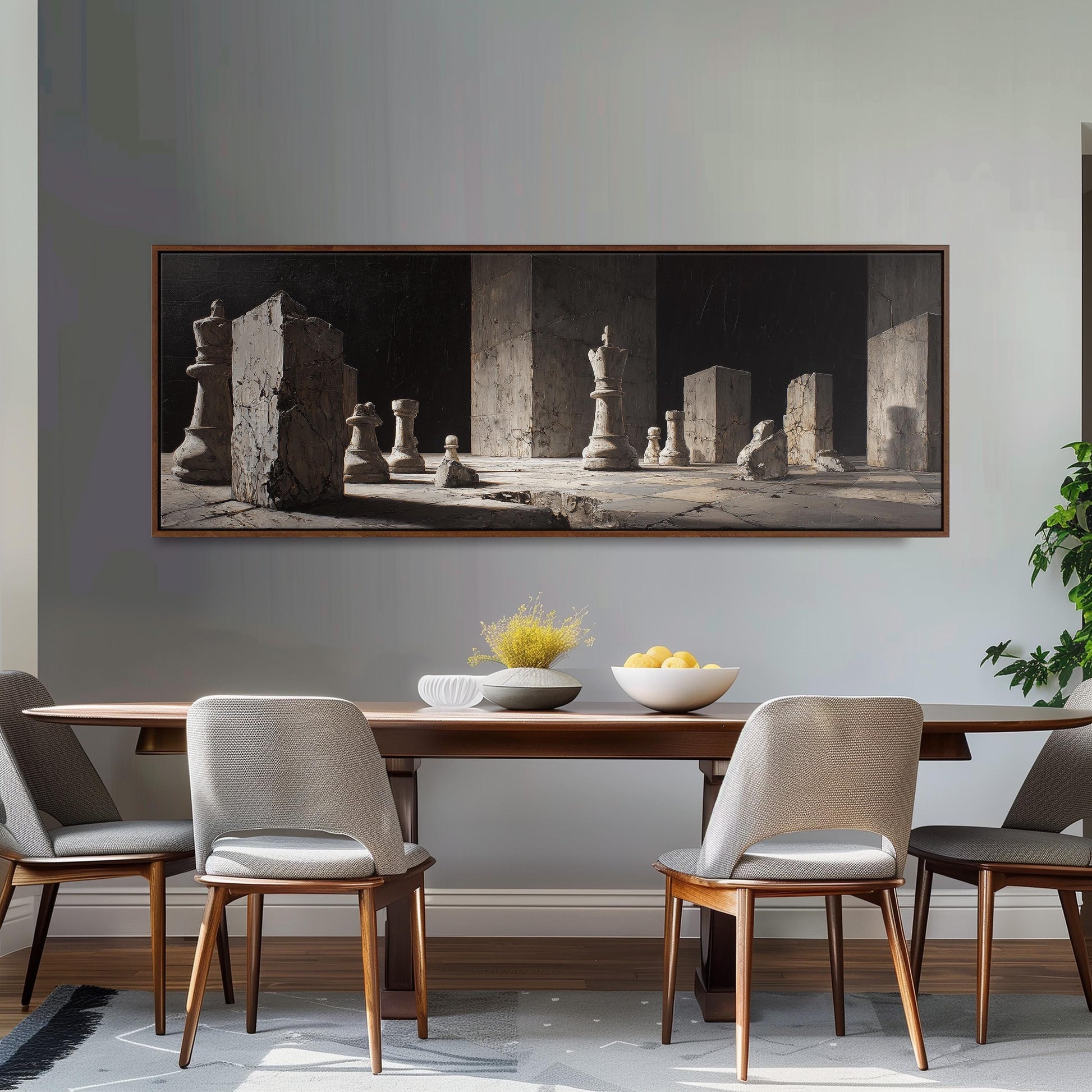 a dining room with a large wooden table and four matching chairs. Above the table, there is a framed black and white photograph depicting a chessboard with chess pieces arranged on it. The photograph is hung on a gray wall above the dining area.