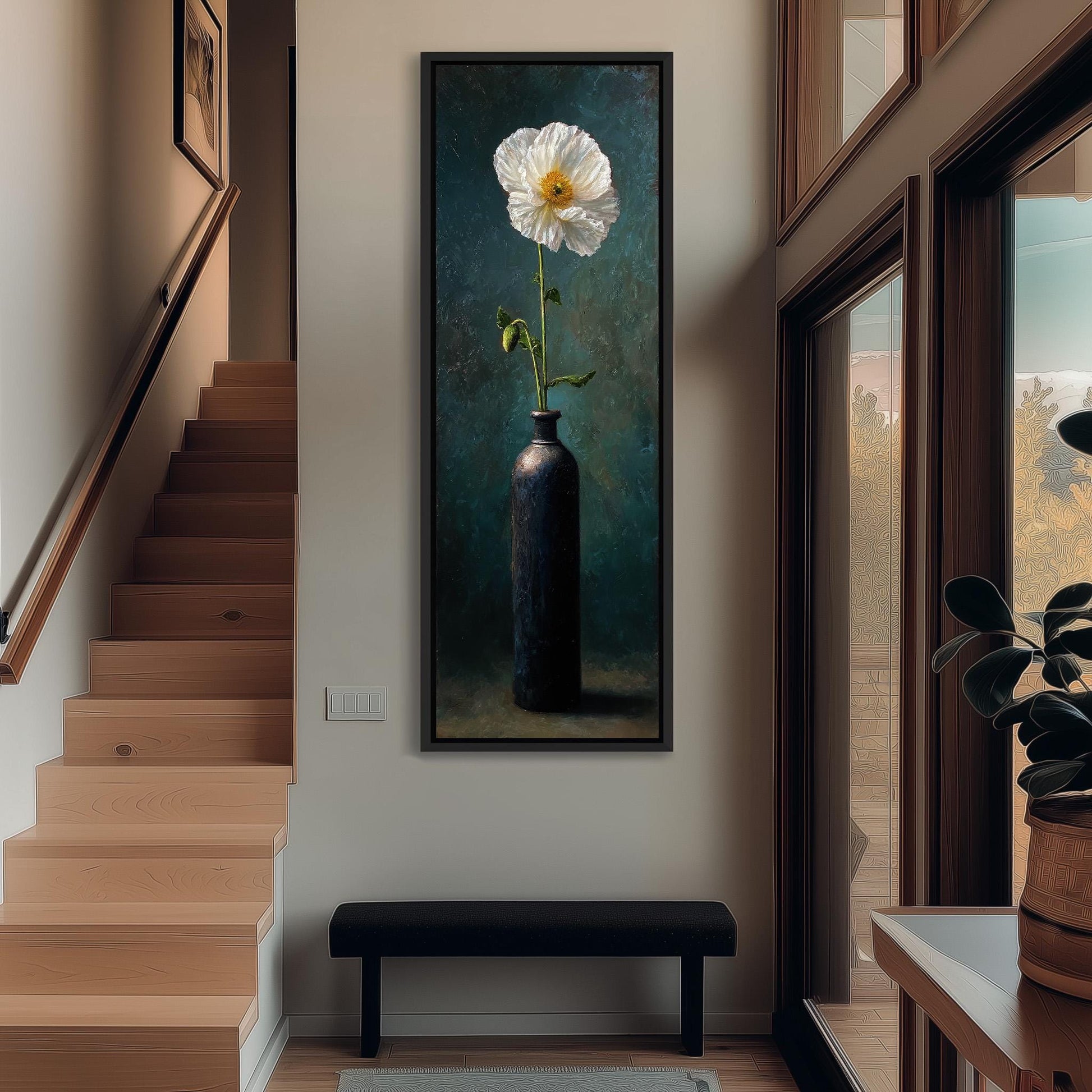 a large painting of a white flower in a black vase hanging on a wall, with a wooden staircase and a bench in the foreground.