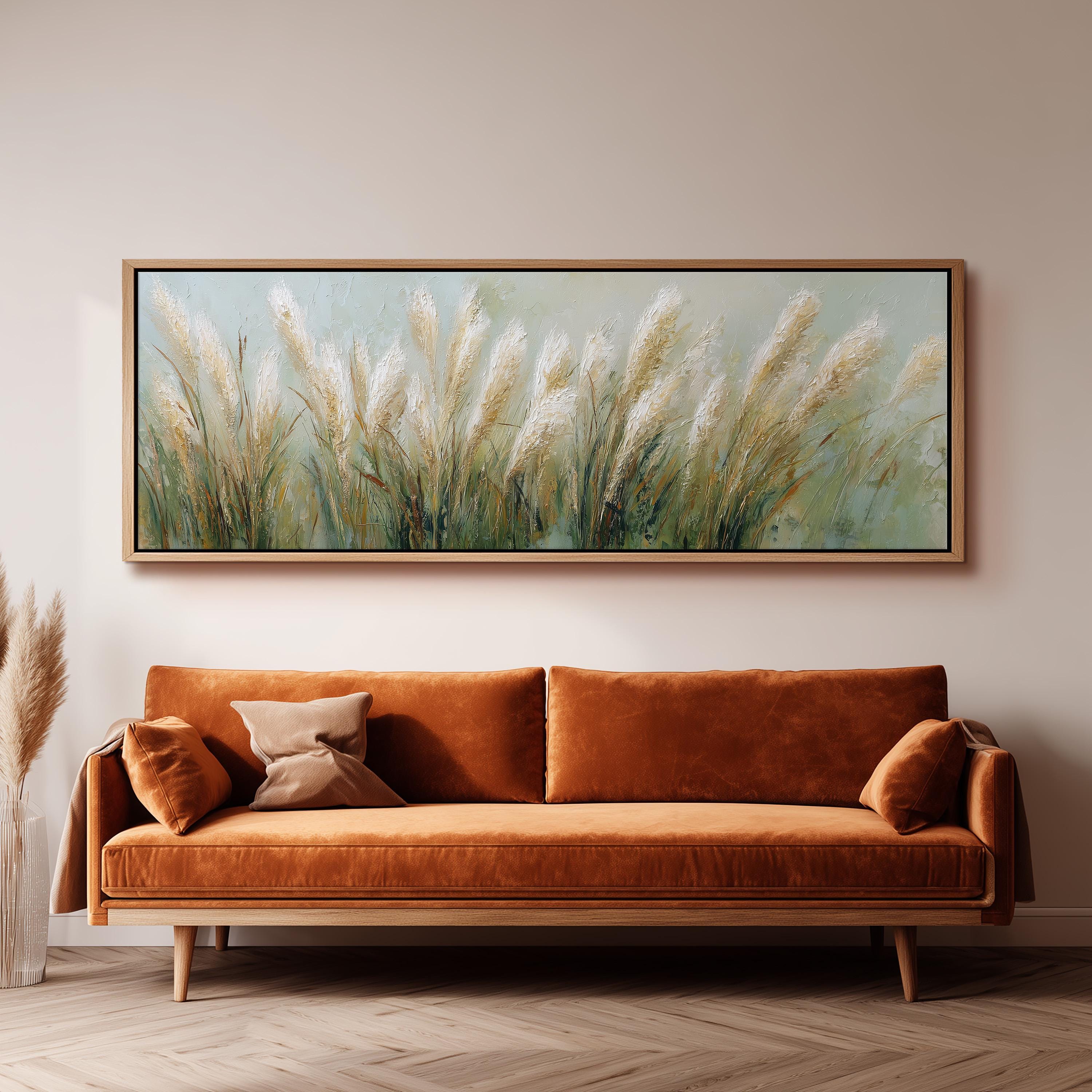 a large painting of tall grass hanging on a wall above a brown sofa with orange cushions.