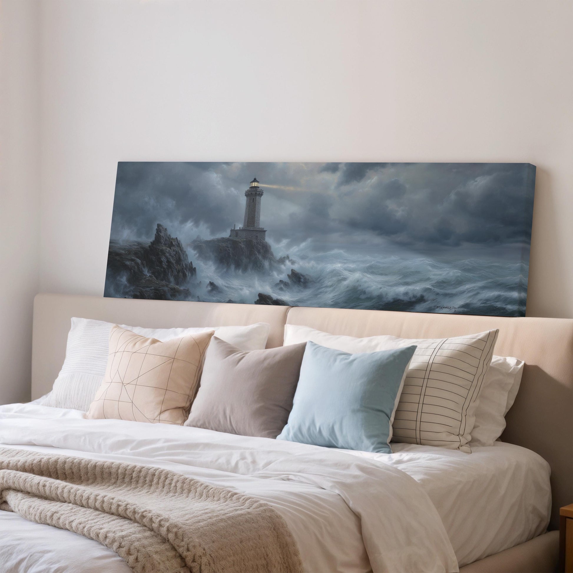 a large painting of a lighthouse on a stormy sea, hanging on a wall above a bed with white pillows and a gray blanket.