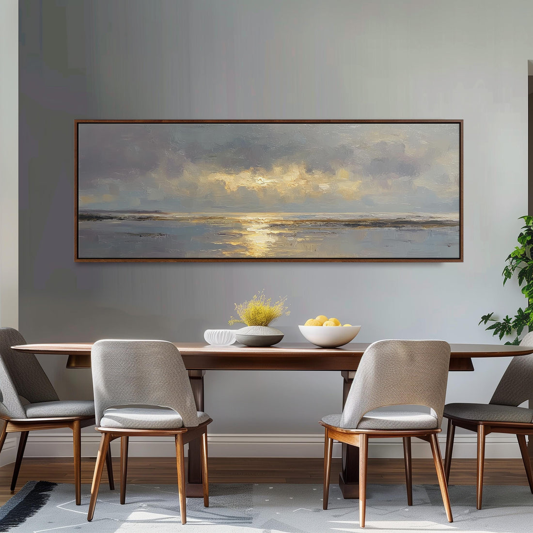 a dining room with a large painting of a serene landscape hanging on the wall above a wooden dining table with four chairs. The table is set with a bowl of fruit and a vase of flowers, creating a cozy and inviting atmosphere.