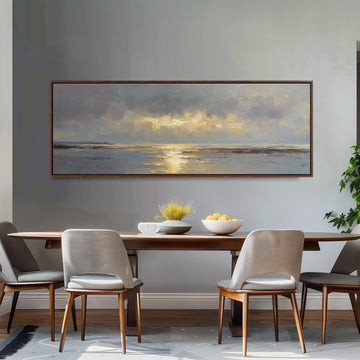 a dining room with a large painting of a serene landscape hanging on the wall above a wooden dining table with four chairs. The table is set with a bowl of fruit and a vase of flowers, creating a cozy and inviting atmosphere.