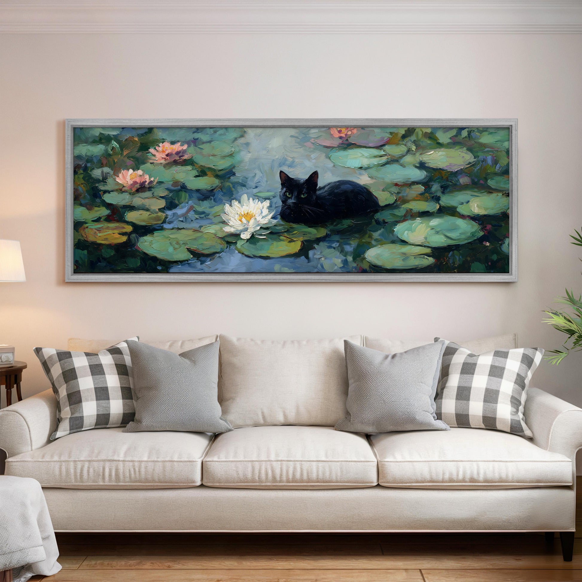 A large painting of a black cat sitting on a lily pad in a pond is displayed on the wall above a white sofa with gray and white patterned pillows.