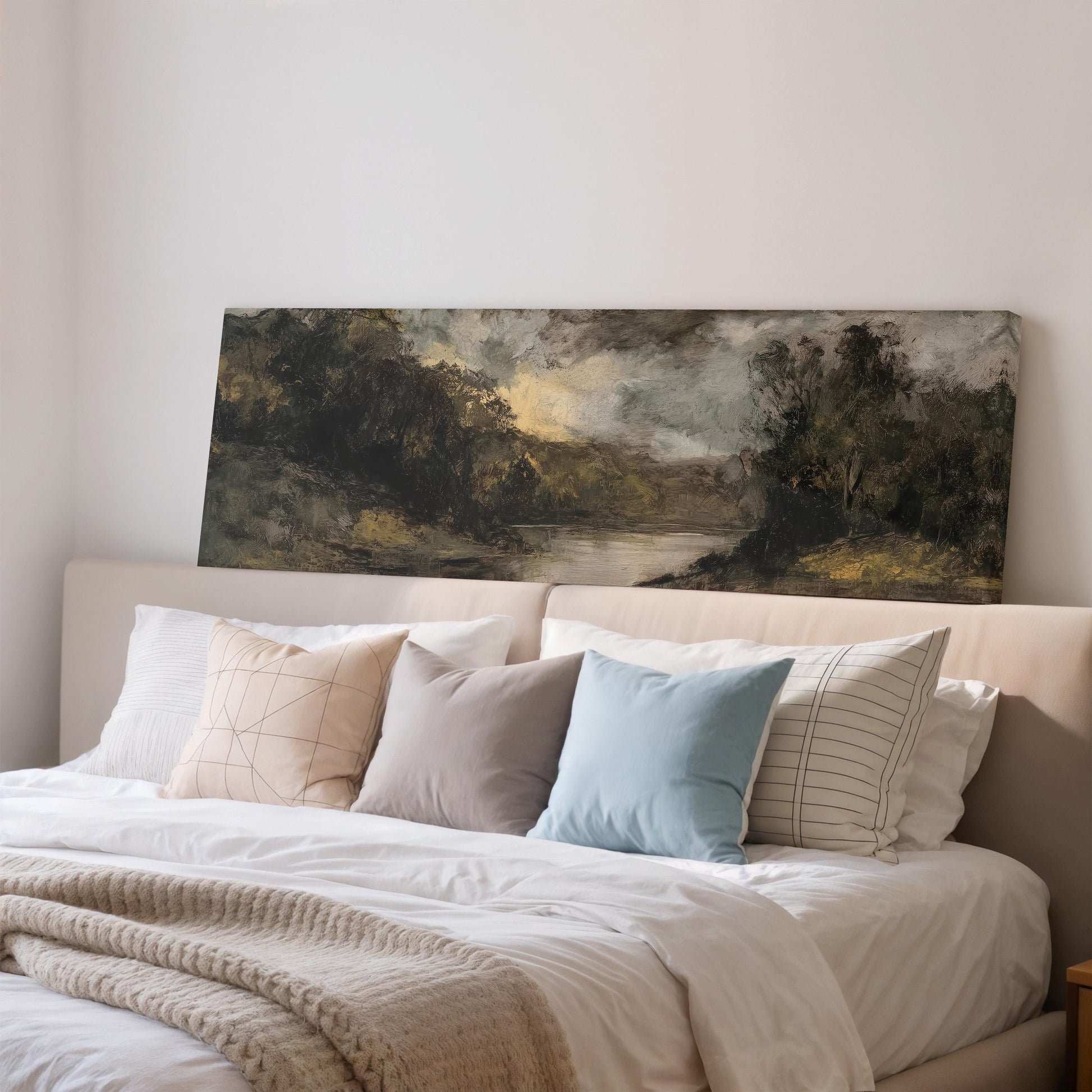 a bedroom with a large painting of a landscape hanging on the wall above a bed with white bedding and various pillows.