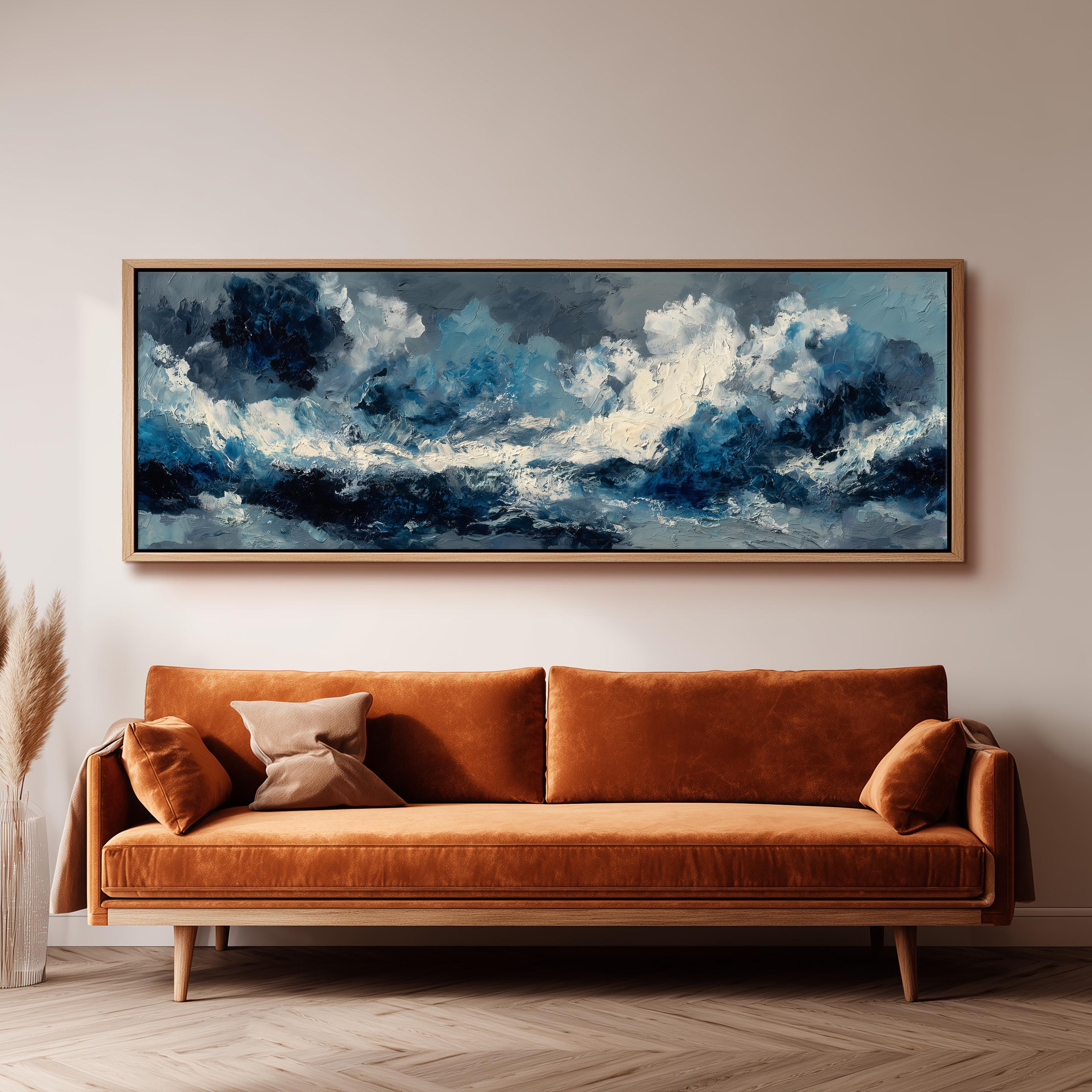 a large, framed painting of a stormy ocean scene hanging on a wall above a brown sofa.