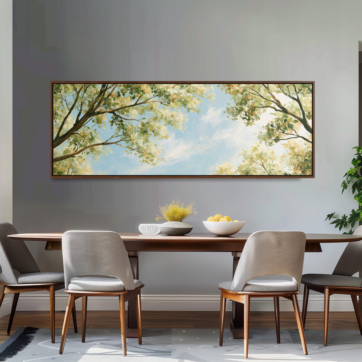 Sunlit leafy branches framing soft clouds long horizontal canvas print above a dining table