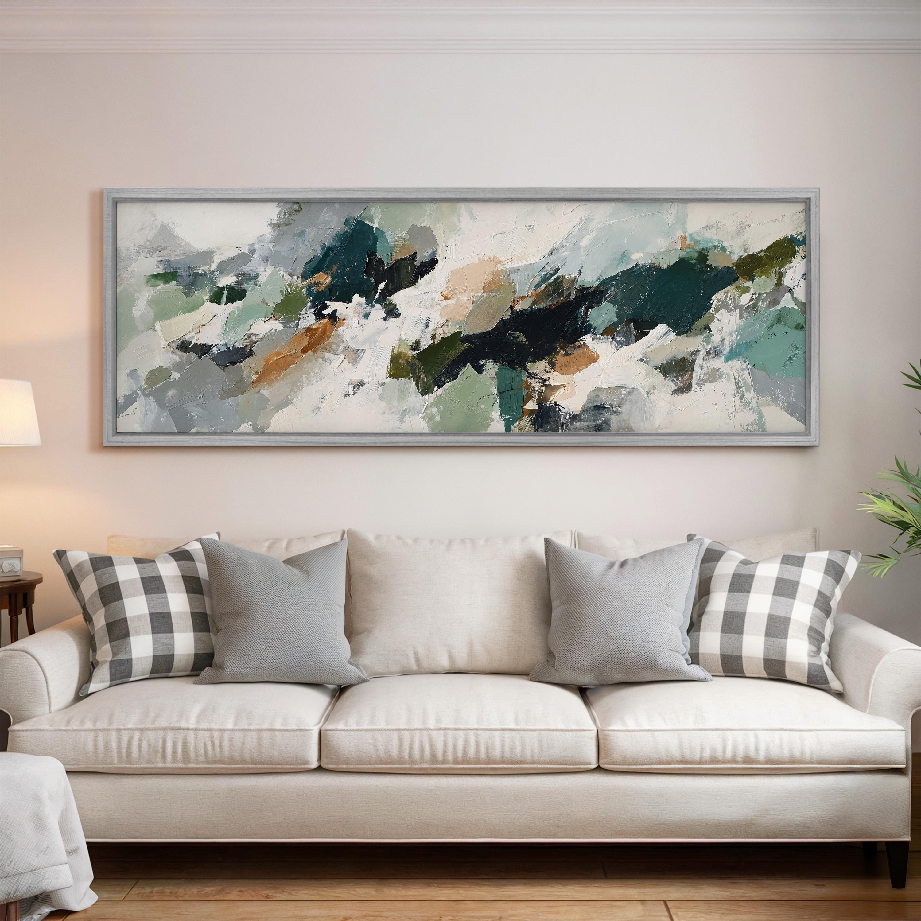a large abstract painting hanging on a wall above a white sofa with gray and white plaid throw pillows.