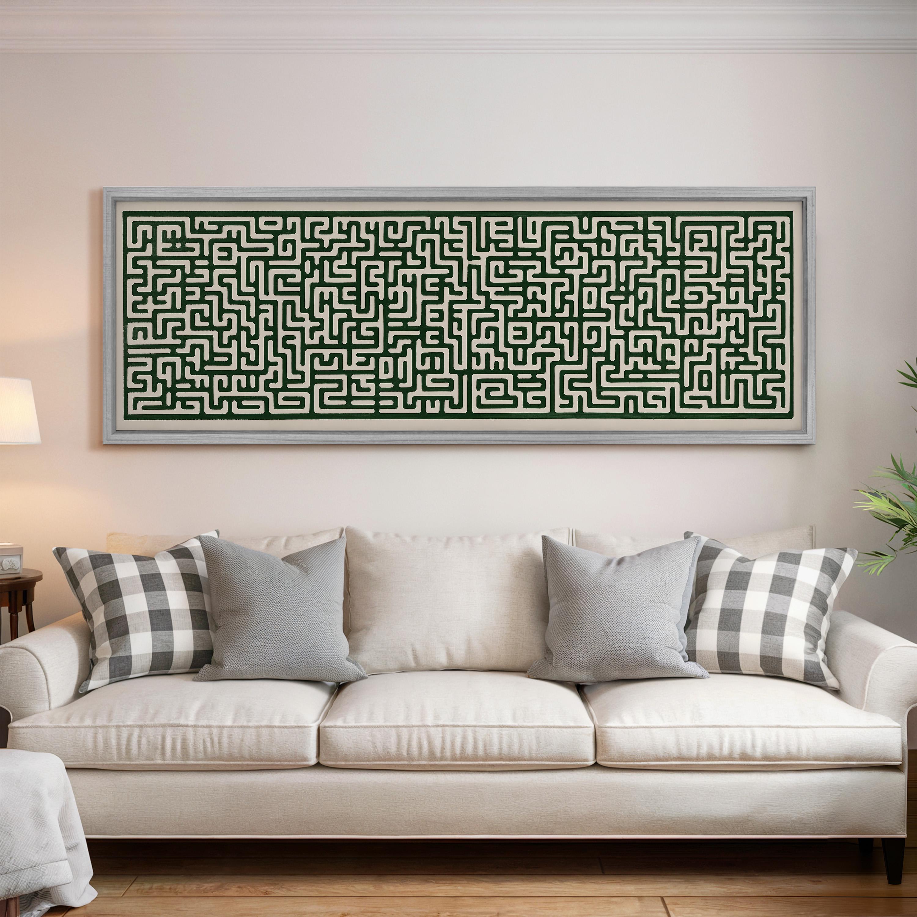 a large, framed painting of a maze on the wall above a white couch with gray and white patterned pillows.