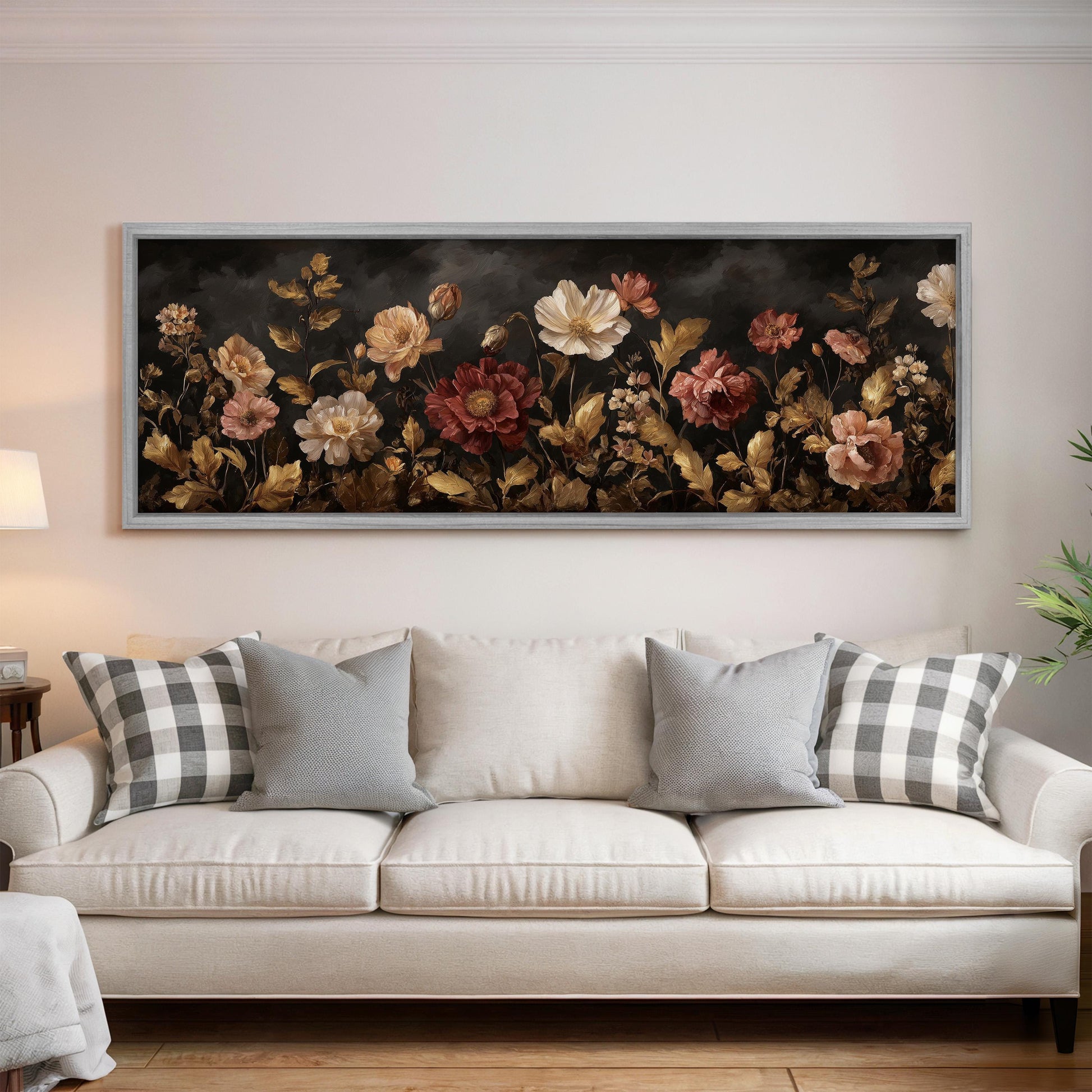 a large, framed painting of a floral arrangement hanging on a wall above a white couch with gray and white plaid throw pillows.