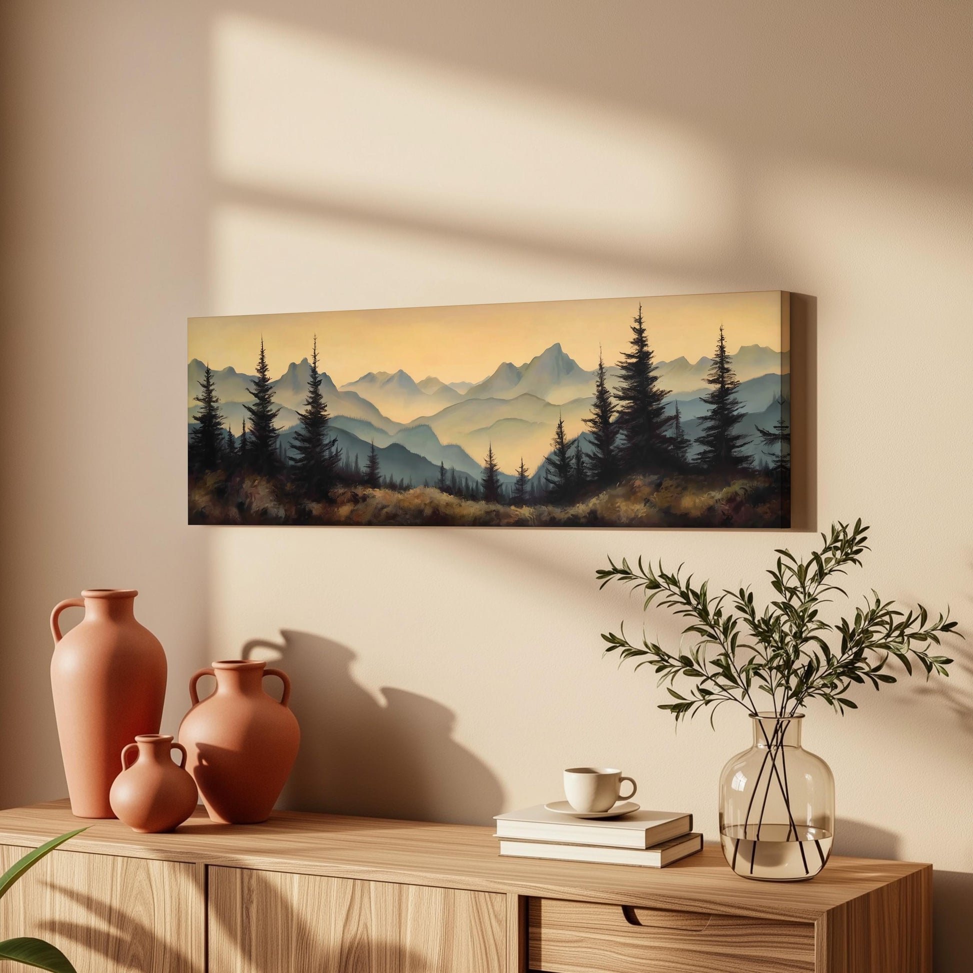 a wooden cabinet with a painting of a mountain landscape hanging on the wall above it. The cabinet also has three orange vases and a glass vase with greenery on top of it.