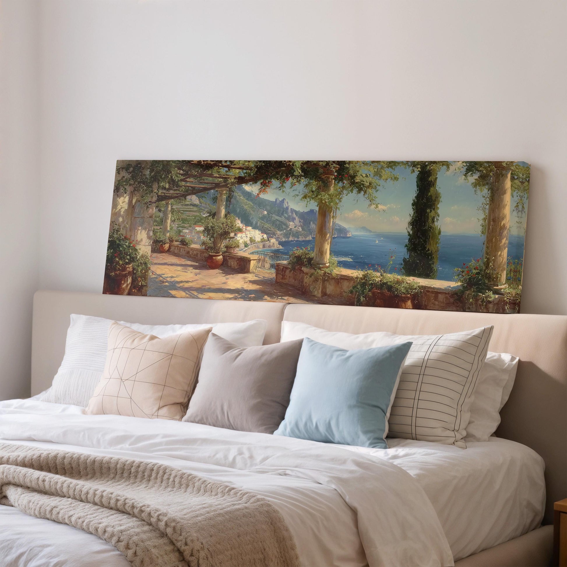 a large painting of a scenic coastal landscape hanging on a wall above a bed with white bedding and pillows.
