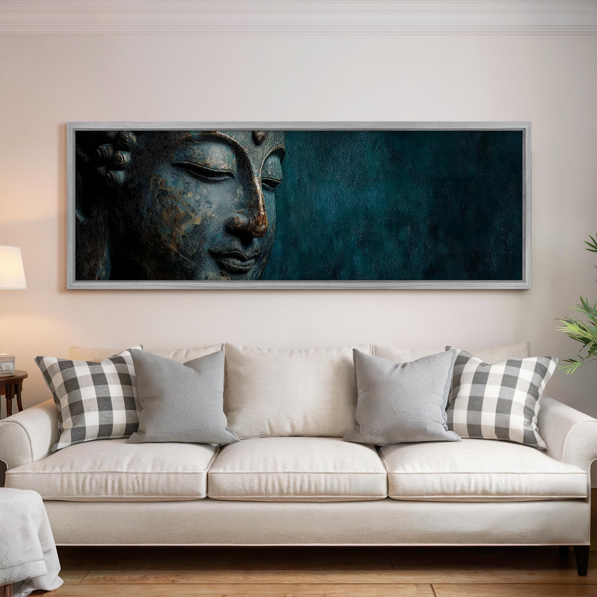 a large framed painting of a Buddha's face on the wall above a white couch with patterned throw pillows.